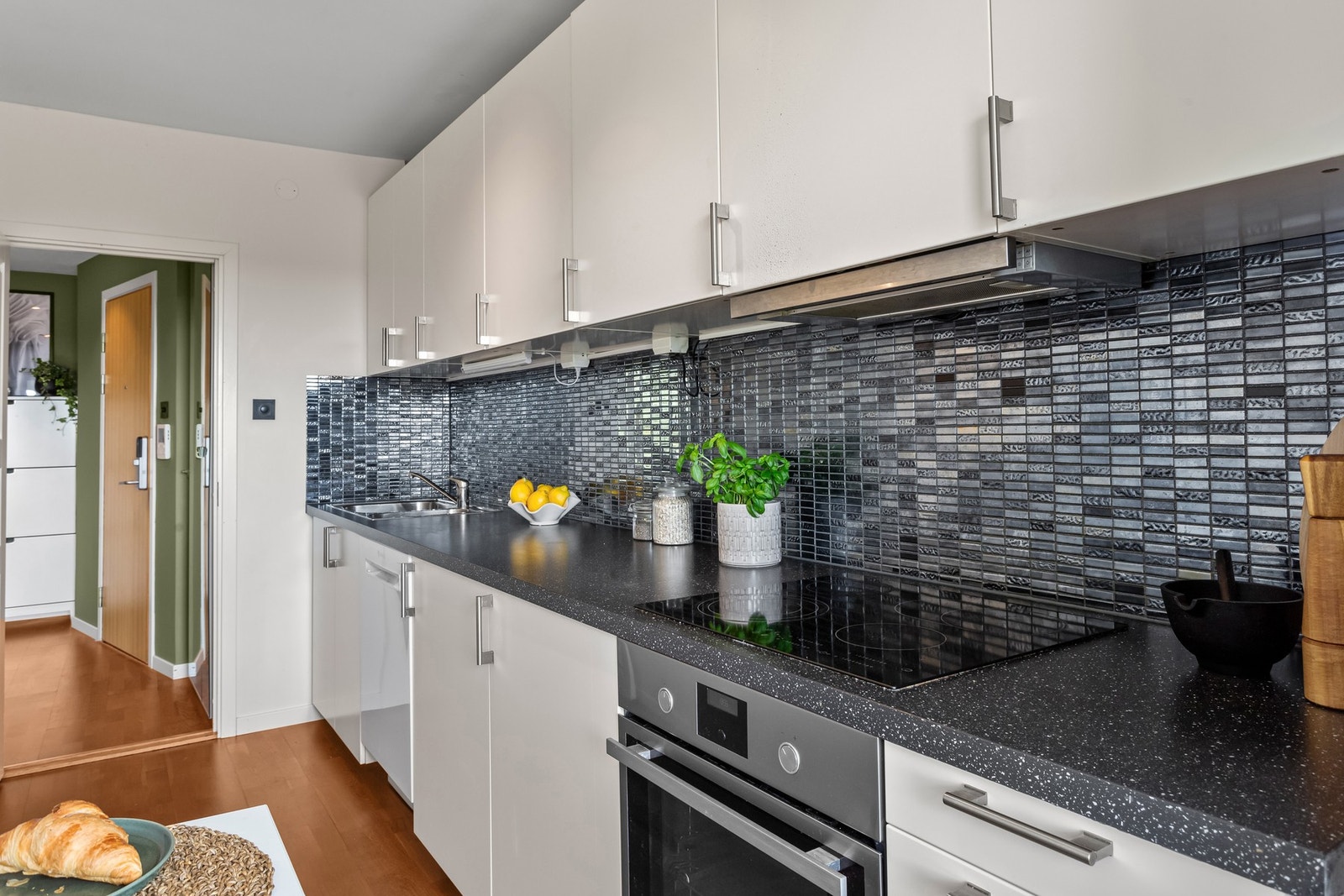 Det er mørke fliser over benken og opplegg for oppvaskmaskin samt plass til kjøle-/fryseskap. Galleribilde