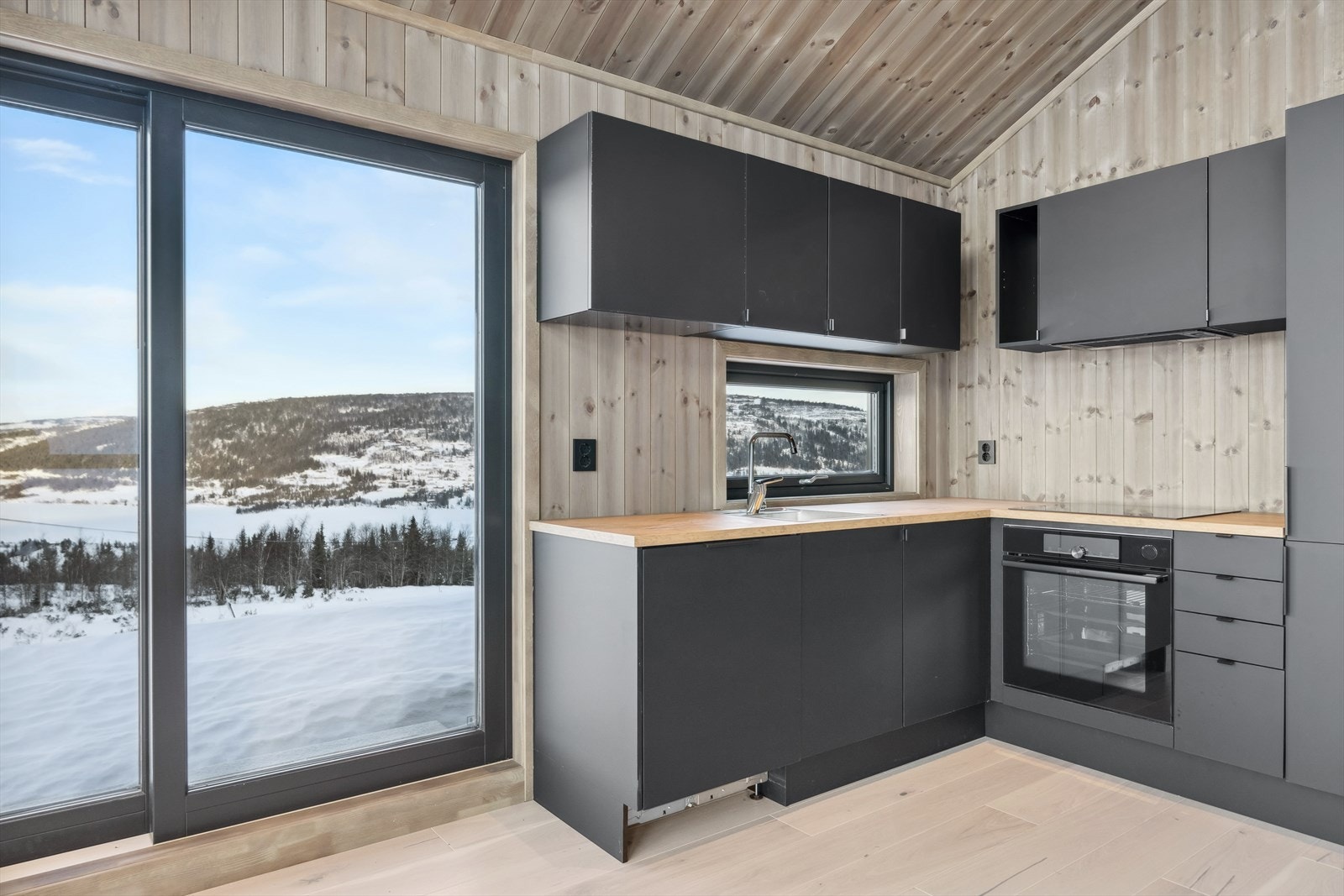 Den stilfulle kjøkkeninnredningen er mørk grå med glatte fronter og sorte detaljer. Galleribilde