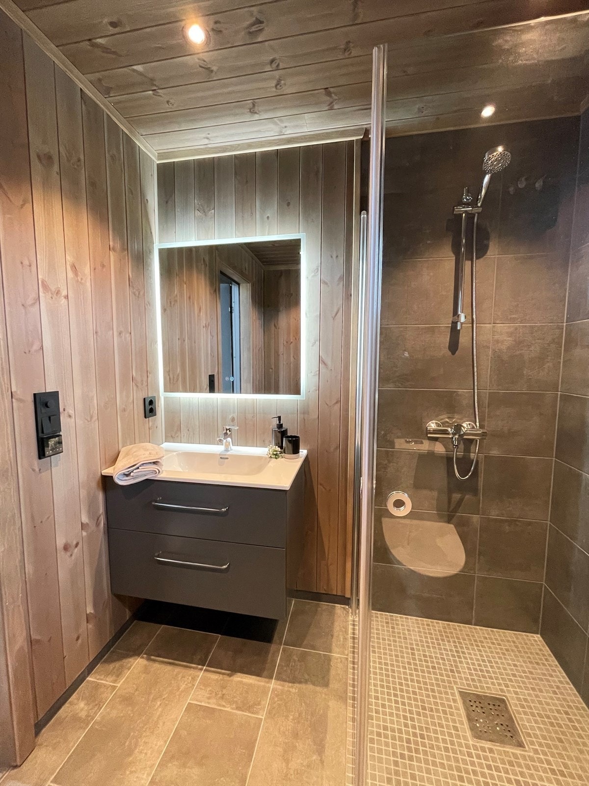 Glassdør inn til flislagt dusjnisje med mosaikkfliser på gulv. Galleribilde