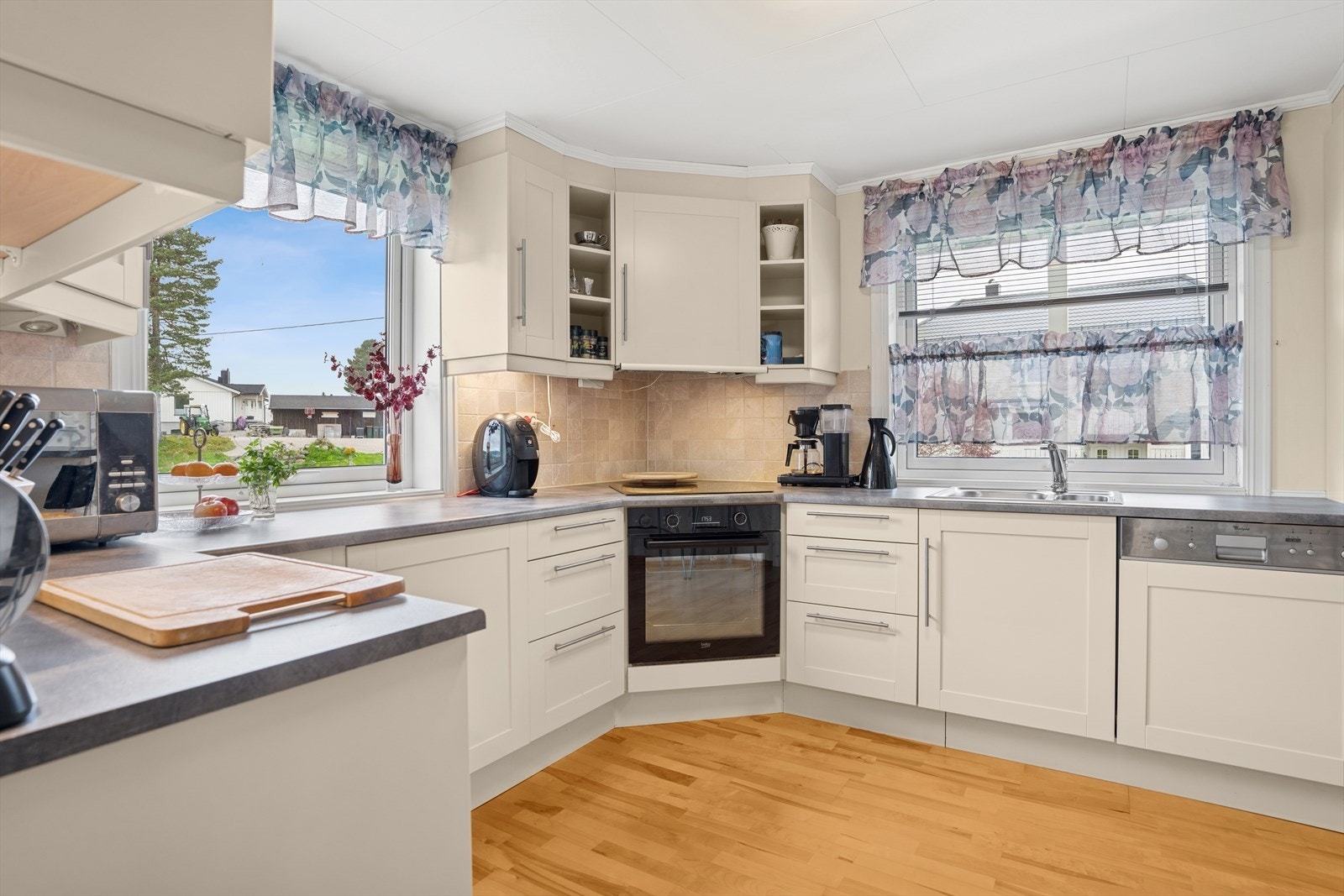 Hvit kjøkkeninnredning med malte, profilerte fronter, takhøye overskap, laminat benkeplater og benkebeslag med 2 kummer og tilhørende armatur. Galleribilde