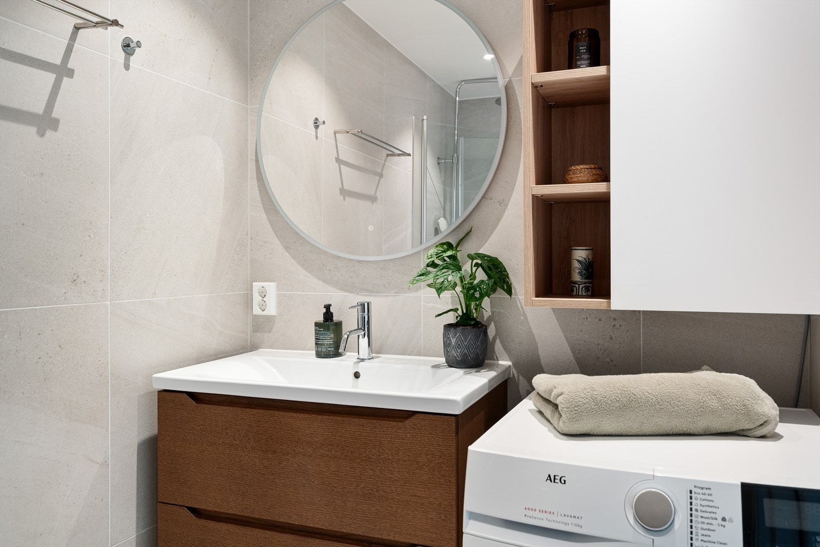 Badet er innredet med vegghengt WC, dusjplass med inn-utadslående dusjvegger, servant med ettgreps blandebatteri i innredning og opplegg for vaskemaskin. Galleribilde