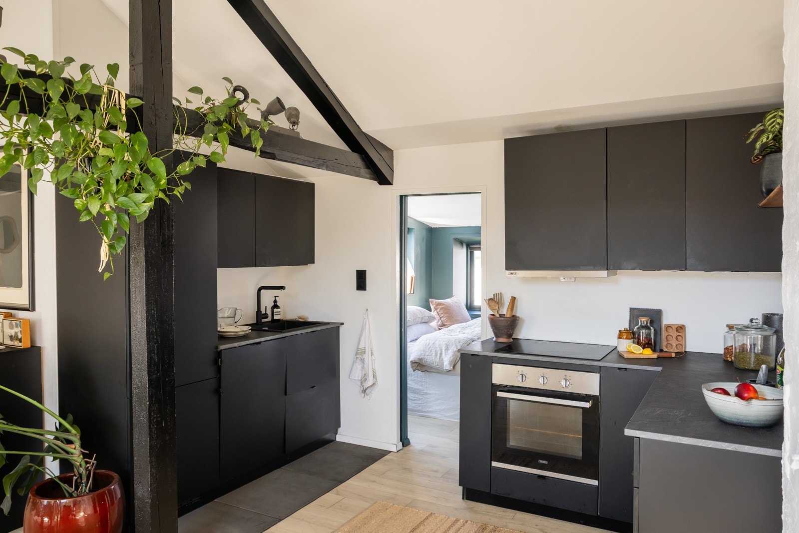 Stilren flislagt vegg over benk, belyst av lysarmatur under overskapene. Det er komfyrvakt og automatisk vannstopper. Galleribilde