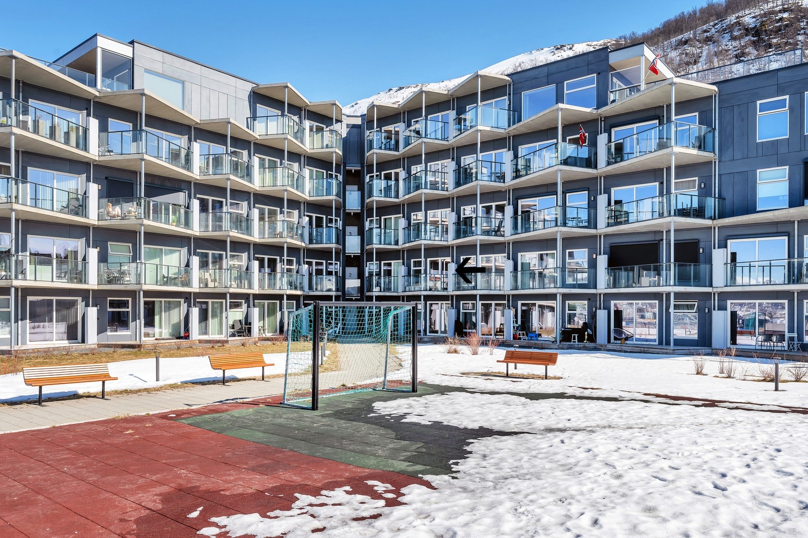 Fellesareal med div. lekestativer, liten fotballbane, plen og benker. Galleribilde