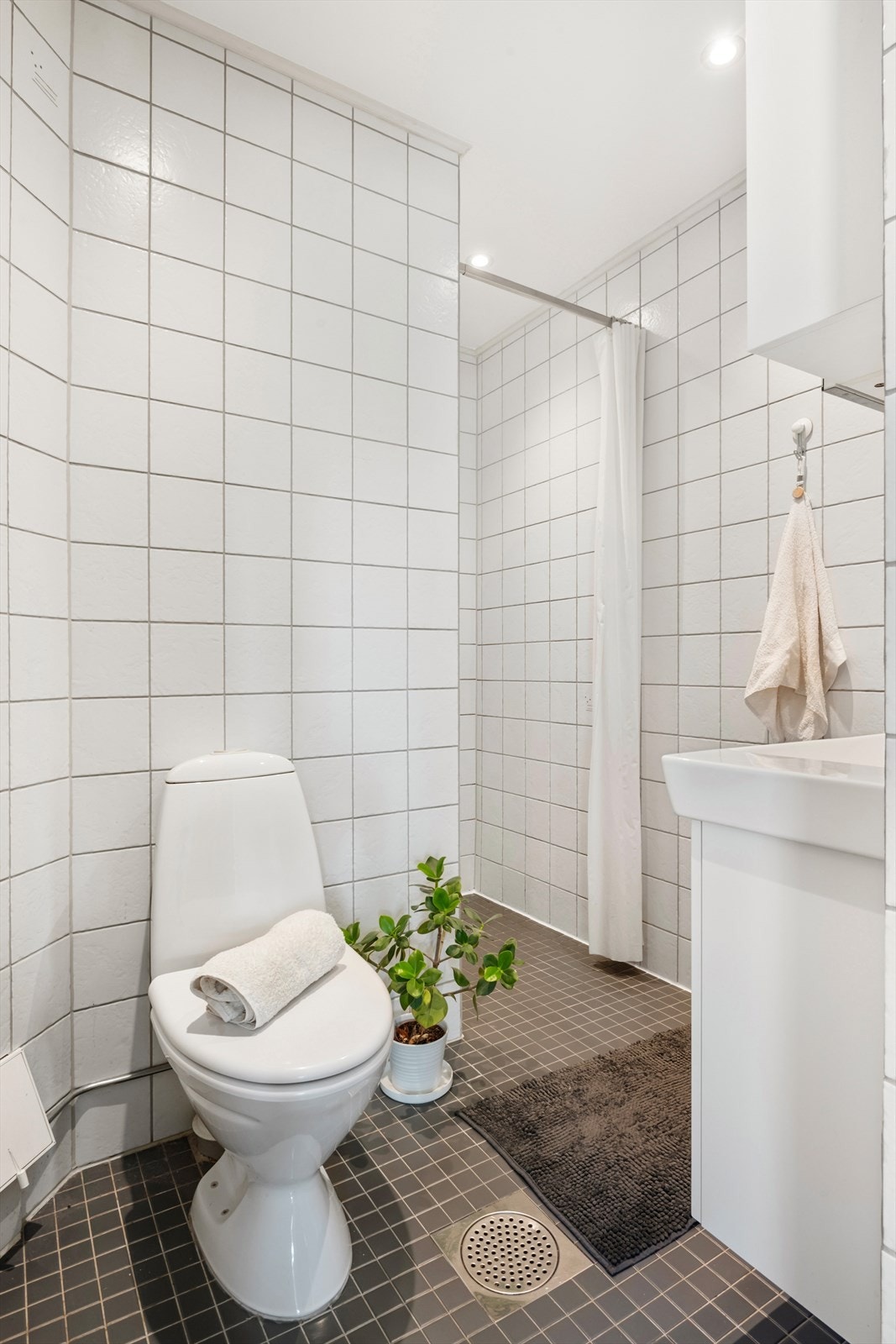 Det er to bad i boligen. Her bad i første plan med varmekabler i gulv, dusj, toalett og servant Galleribilde