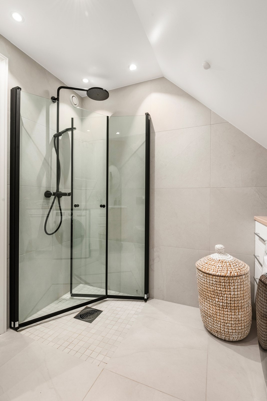 Regnfalldusj og innsvingbare dusjdører i glass. Veggmontert toalett, servant og rikelig med oppbevaring. Galleribilde