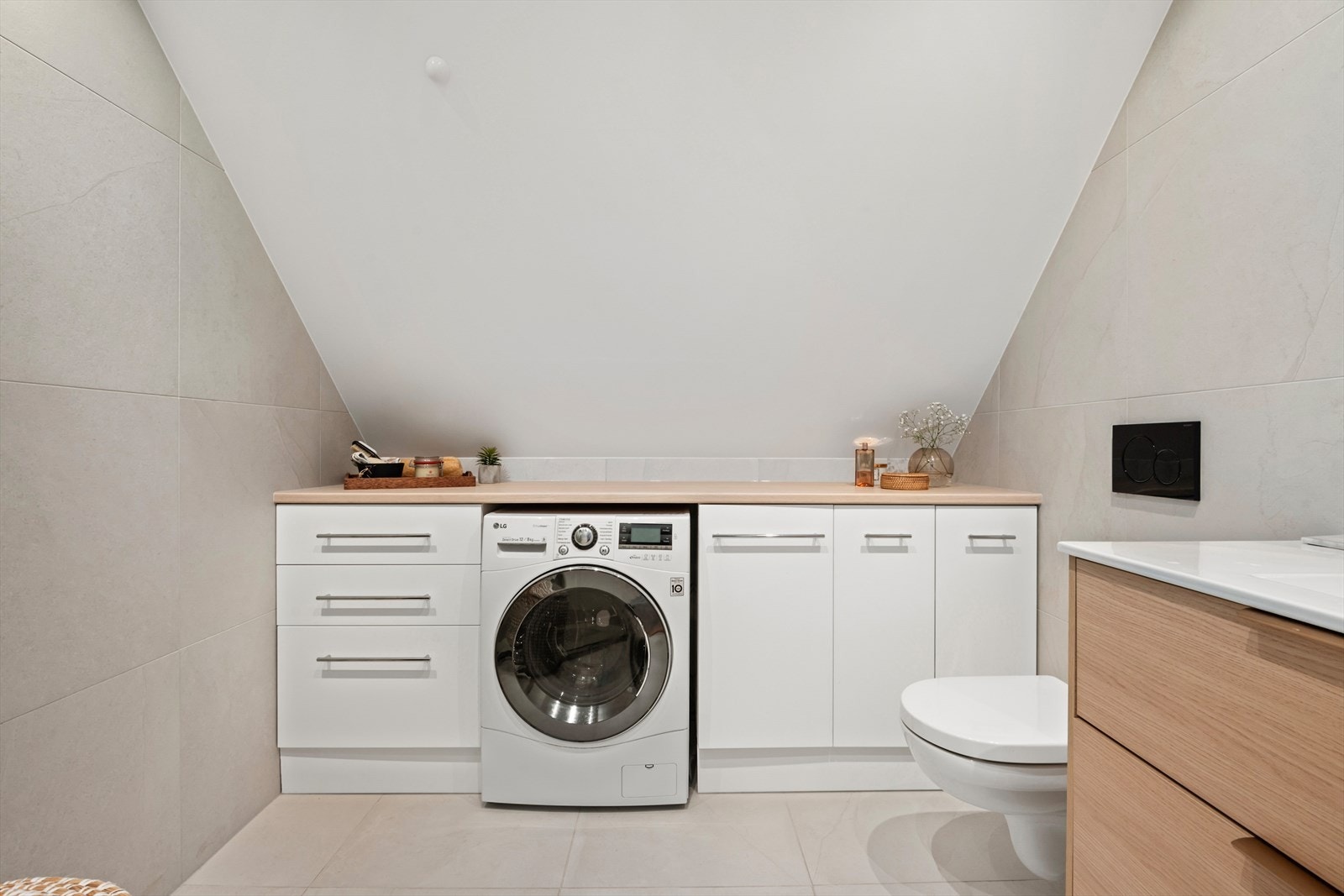 Badet har praktisk plass for vaskemaskin og godt med oppbevaring i plassbygget skap Galleribilde