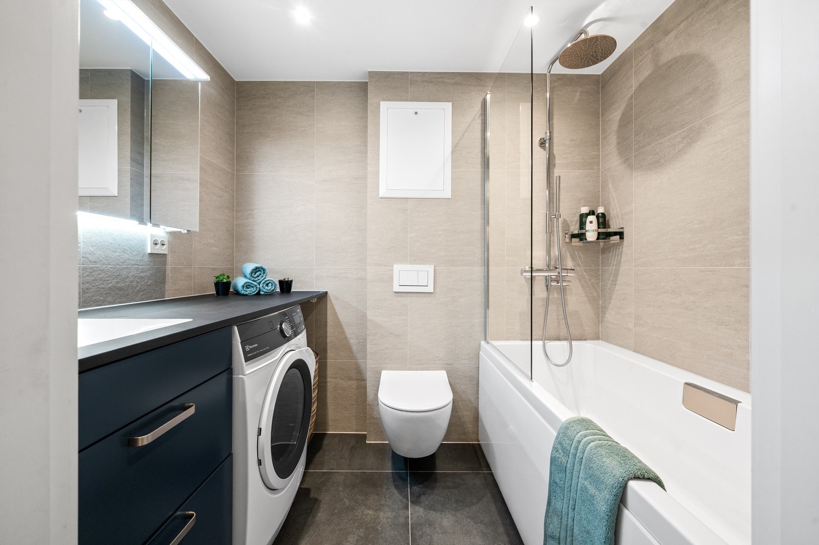 Badet ble totalrenovert i 2024 og er lekkert flislagt på gulv og vegger med varme i gulvet. Baderomsinnredningen er levert av Designa og består av vegghengt servantskuffer med laminat benkeplate og underlimt vask. Galleribilde