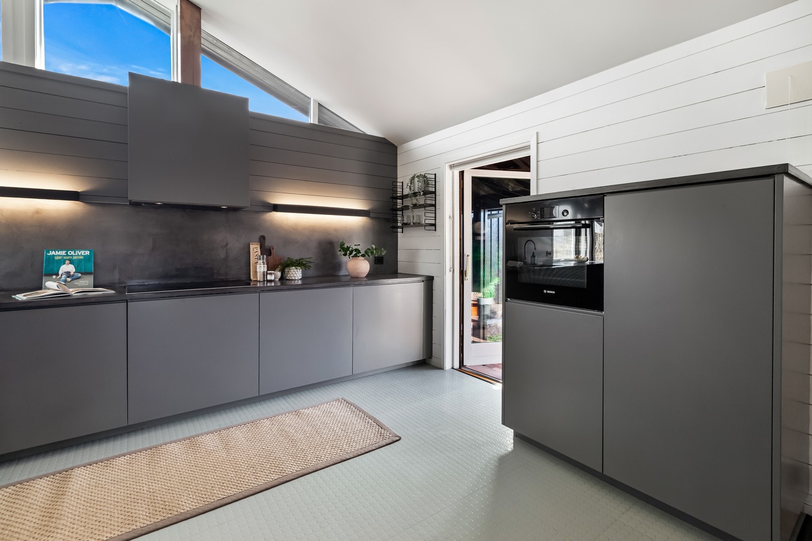 Det er gode arbeidsflater på kjøkkenet. Panelet sammen med belysningen på veggen gir et lekkert uttrykk. Galleribilde