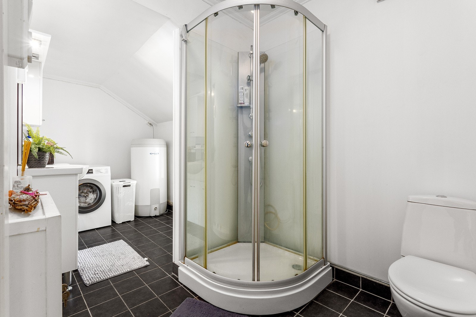 Praktisk bad/vaskerom med flislagt gulv og lyse overflater. Galleribilde