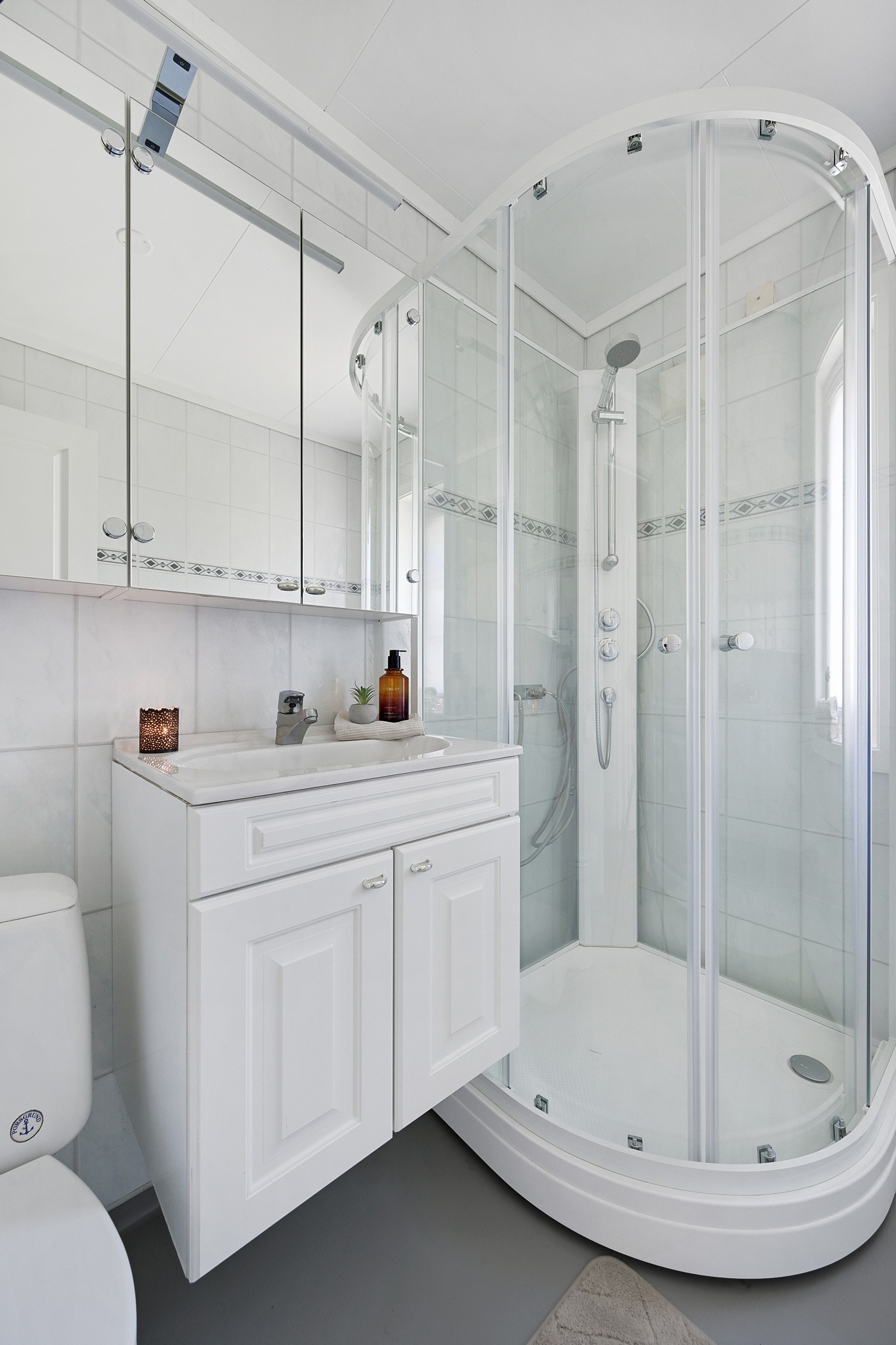 Badet er innredet med dusjkabinett, klosett, speilskap og pen baderomsinnredning. Galleribilde