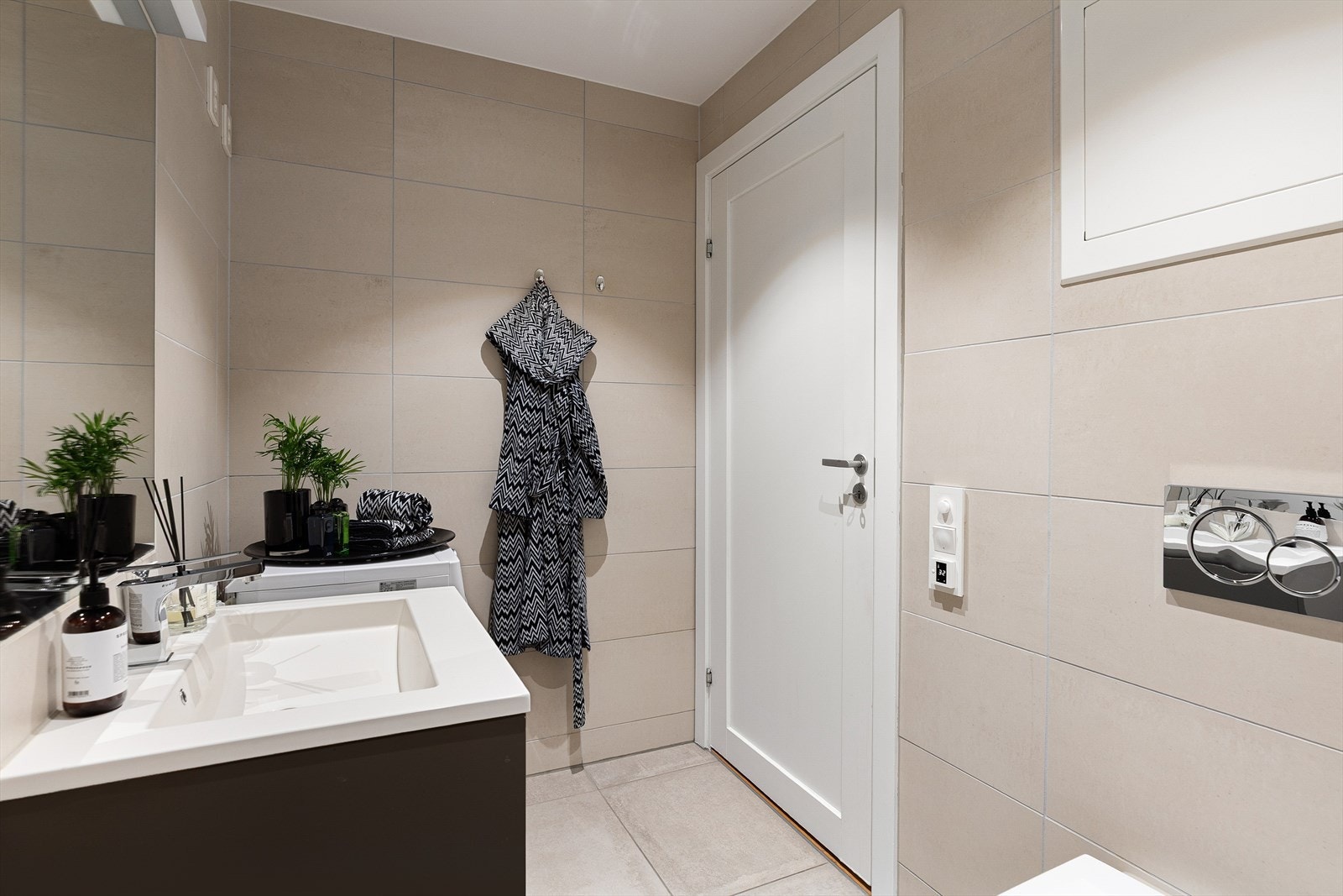 Badet er innredet med veggmontert WC, dusjnisje med glassvegg, servant med ettgreps blandebatteri i praktisk innredning samt opplegg for vaskemaskin. Det er mekanisk avtrekk og vannbåren gulvvarme. Galleribilde