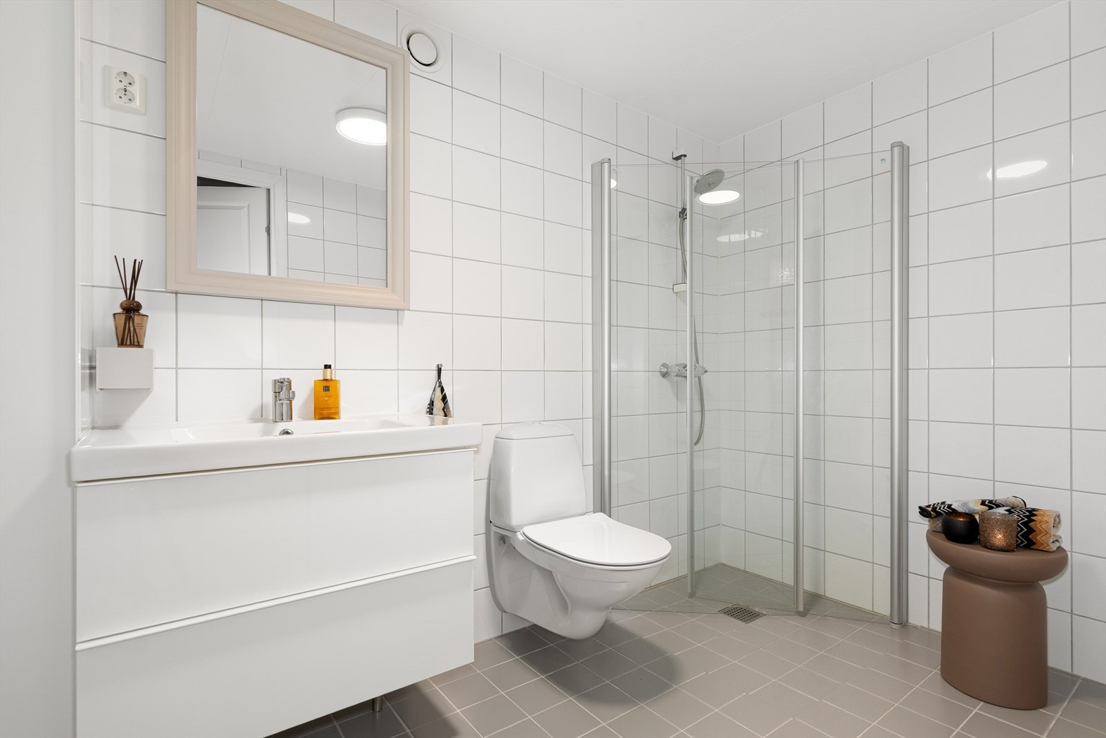 Innredningen består av et stilrent servantskap med nedfelt servant, vegghengt klosett og en romslig dusjsone med innfellbare dusjdører i herdet glass. Galleribilde