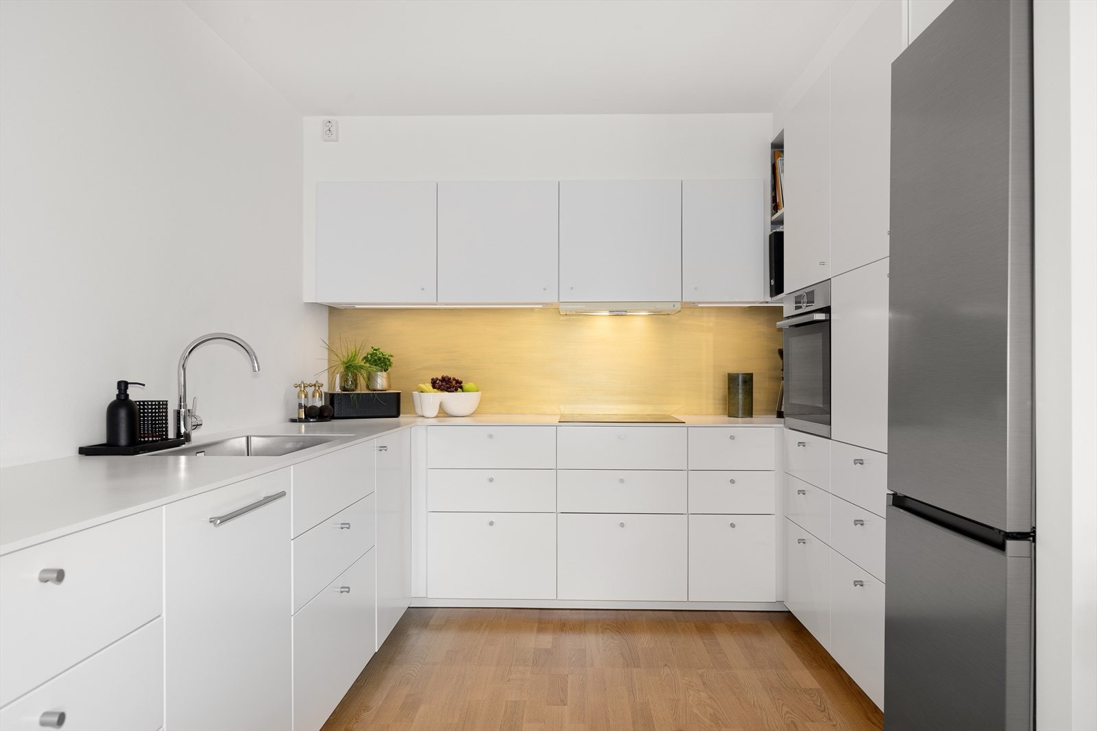 Kjøkkenet er utstyrt med integrerte hvitevarer, inkludert induksjonsplatetopp, stekeovn og oppvaskmaskin, samt et frittstående kjøleskap med fryser. Galleribilde