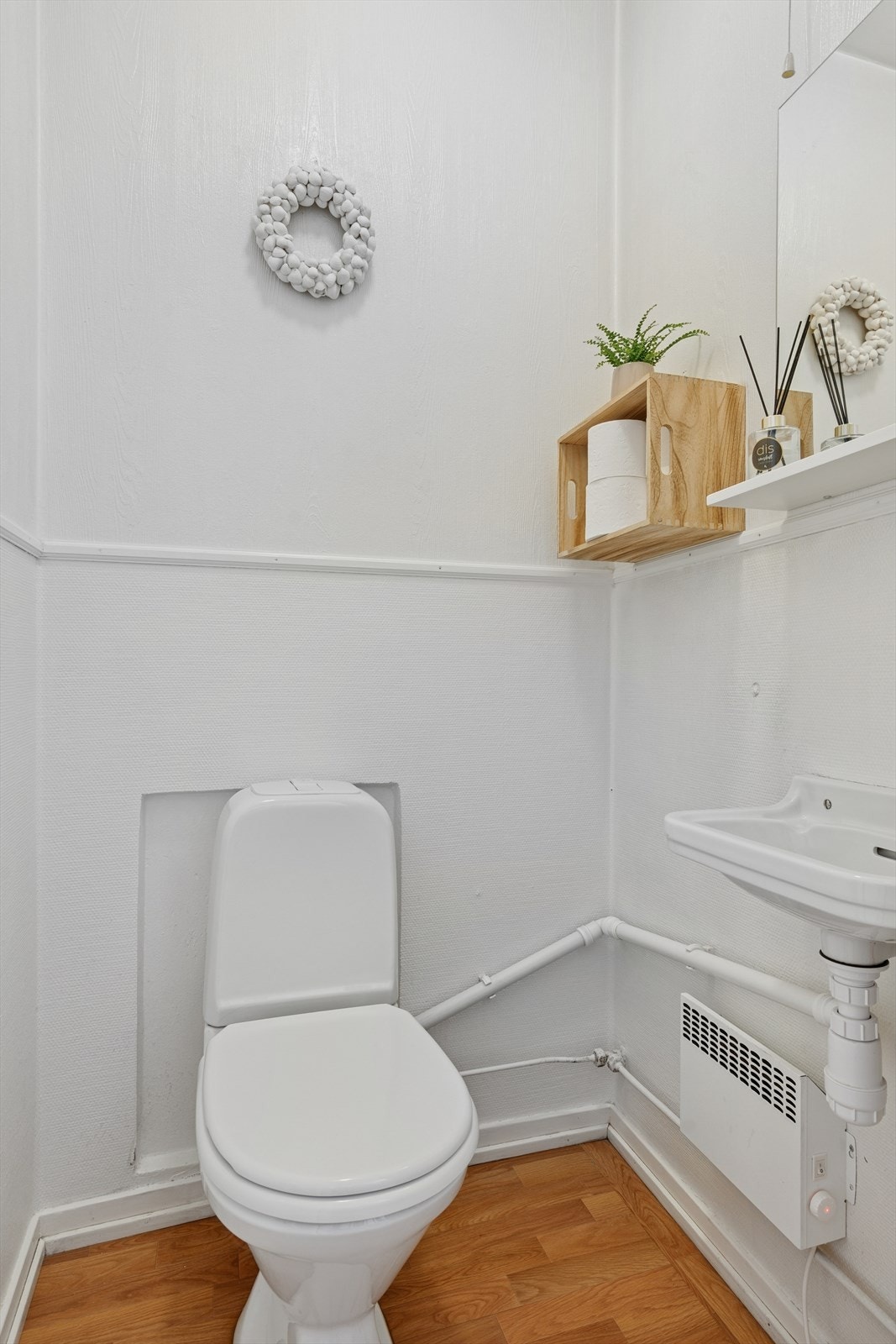 Separat wc-rom med gulvstående toalett og enkel servant på vegg. Galleribilde