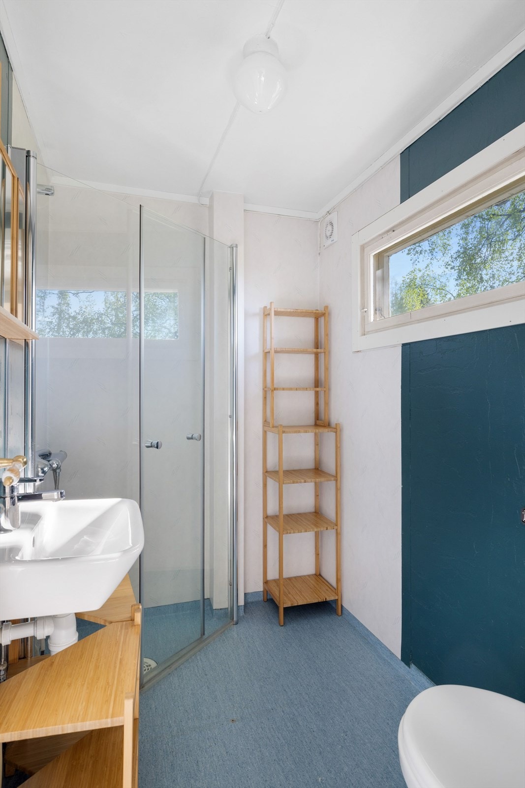 Badet liggeri 1. etasje og har belegg på gulvet. Rommet er utstyrt med gulvmontert toalett, dusjhjørne med innfellbare dører og vegghengt dusjbatteri, samt håndvask. Galleribilde