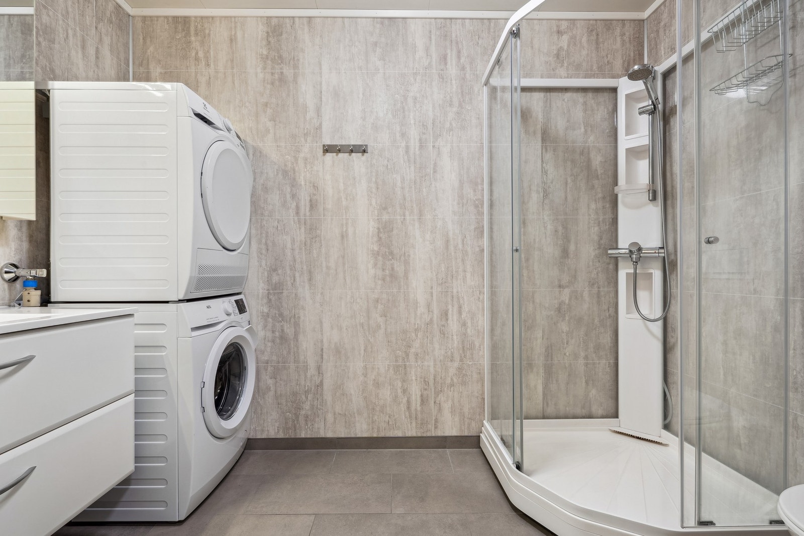 Rommet har innredning med nedfelt servant, veggmontert toalett, dusjkabinett og opplegg for vaskemaskin. Galleribilde