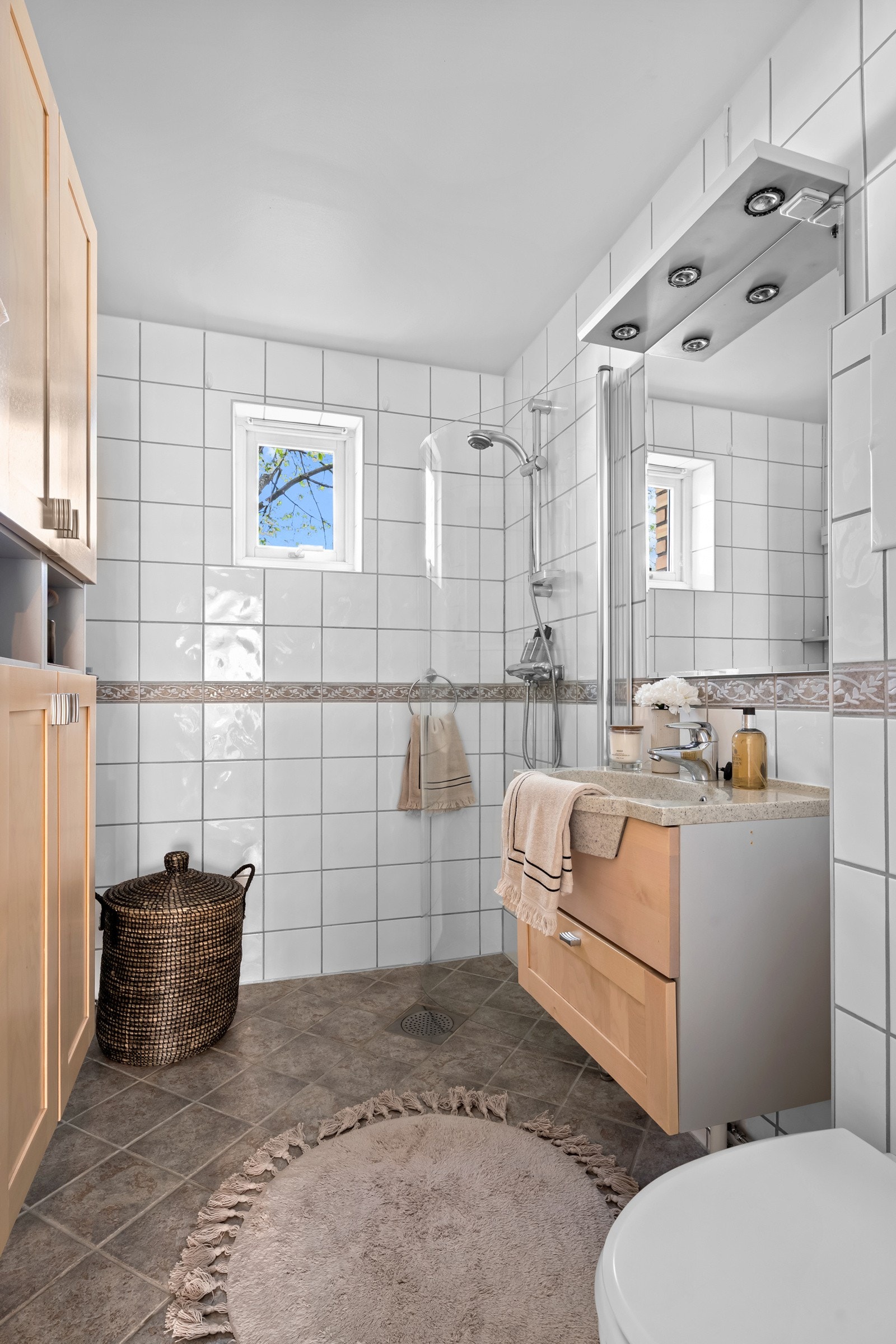 Flislagt bad med varmekabler, dusjnisje, veggmontert servantskap og toalett samt opplegg for vaskemaskin Galleribilde