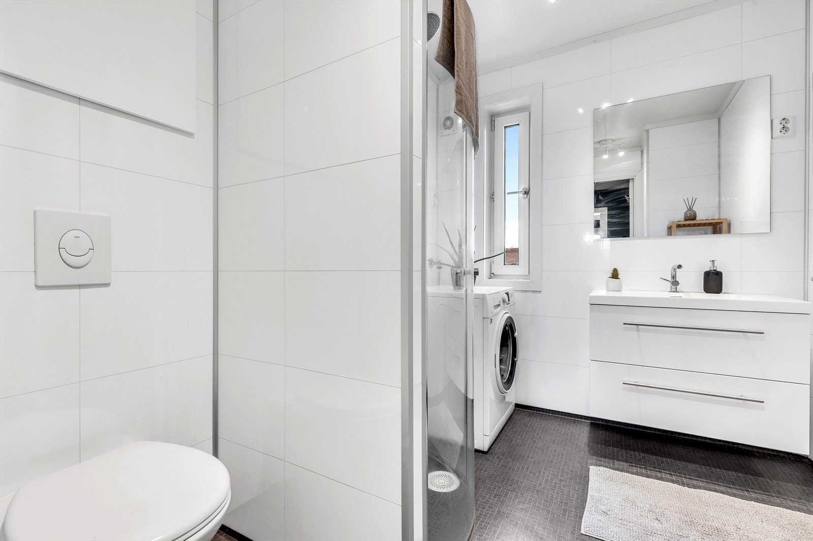 Badet er praktisk inndelt med en egen sone for dusj og en separat sone for toalettet, noe som bidrar til en funksjonell bruk av rommet. Galleribilde