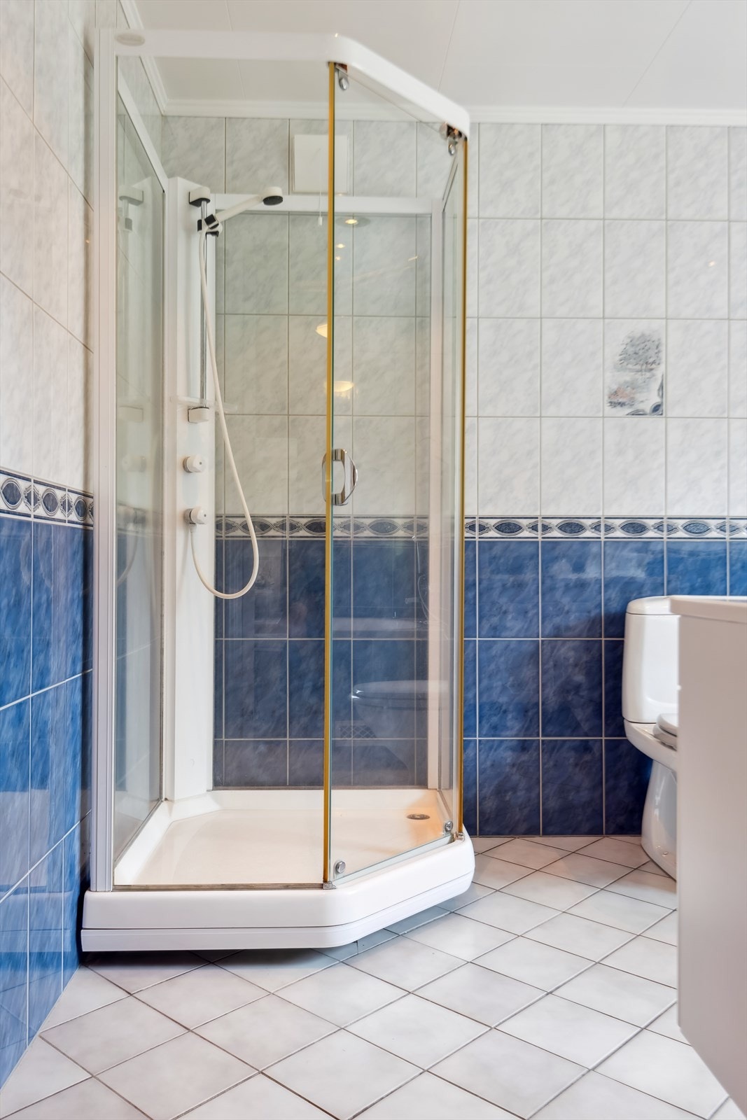 Badet er innredet med servant i møbelinnredning, gulvmontert toalett, dusjkabinett og innfliset badekar. Galleribilde