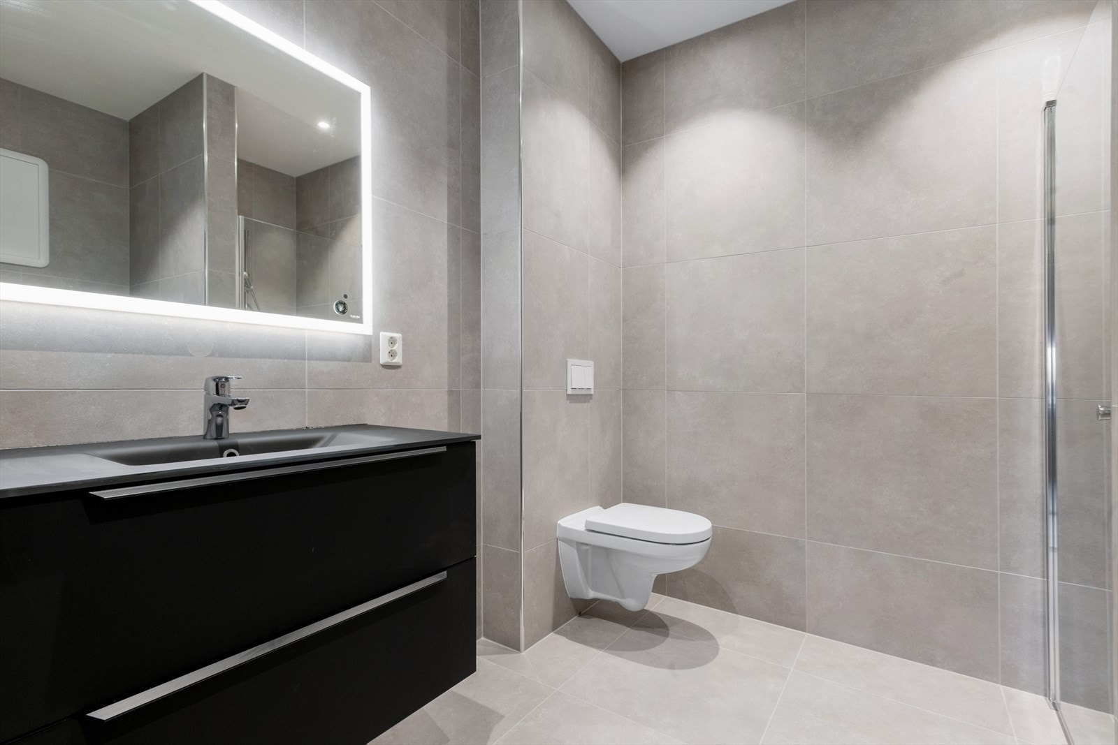Badet i 1. etasje er heilflisa med store fliser i dus fargetone Galleribilde