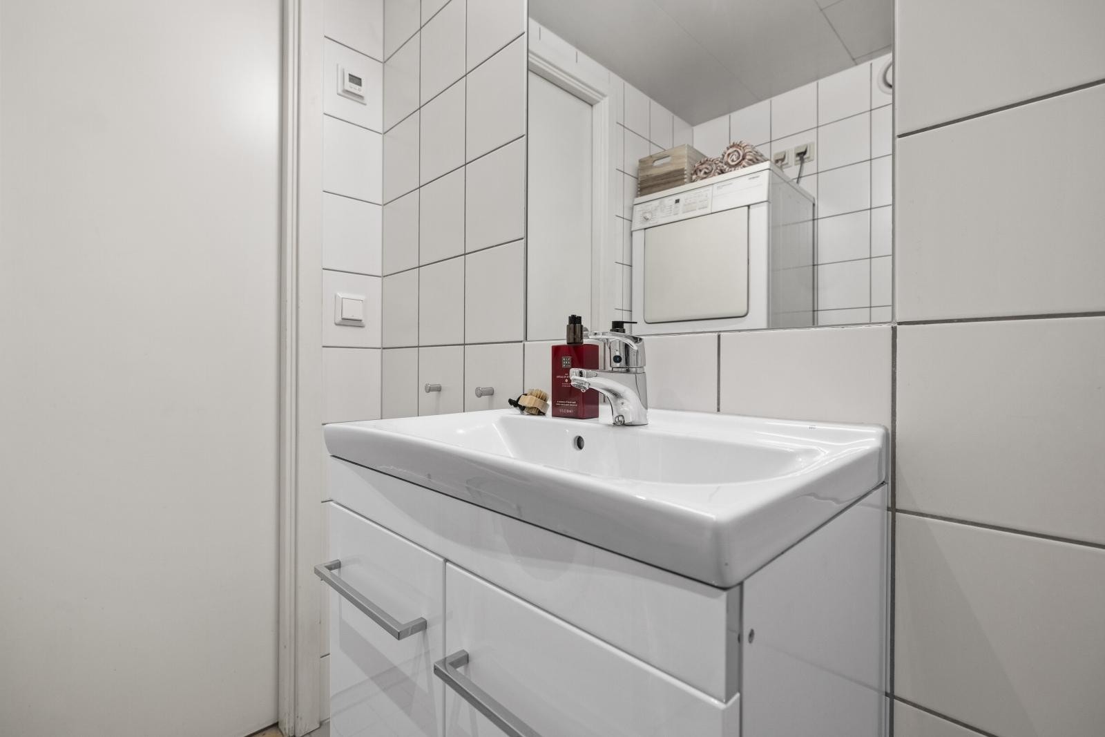 Lyst flislagt bad med opplegg for vaskemaskin og tørketrommel Galleribilde