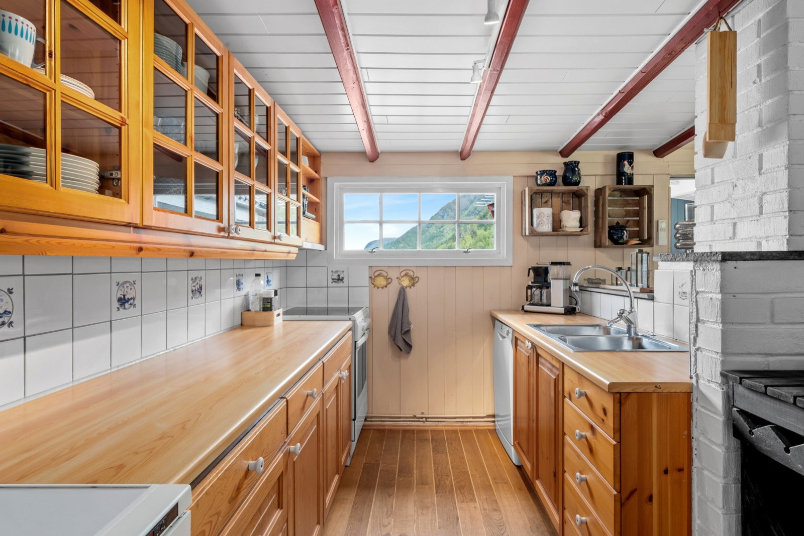 Kjøkkenet har en tradisjonell innredning med trehvite fronter, ventilator og opplegg for oppvaskmaskin. Galleribilde