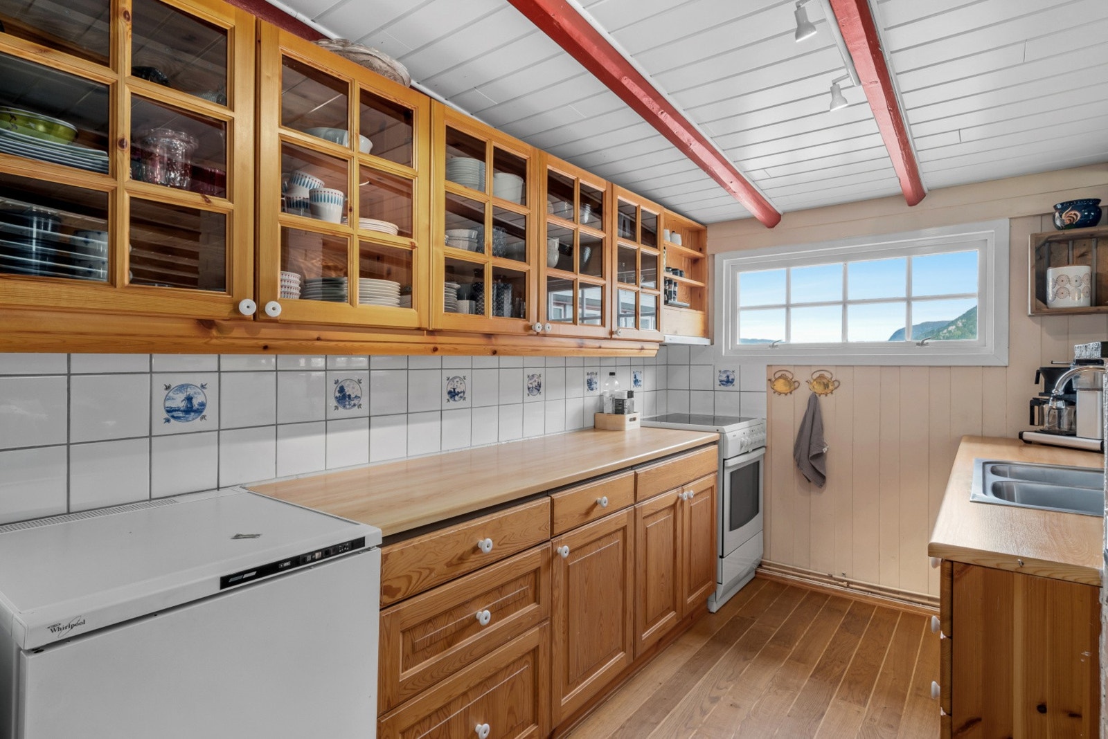 Det er vitrinedører på overskapene, fliser over benken og vindu i enden. Dette gjør arbeidssonen ekstra hyggelig. Galleribilde