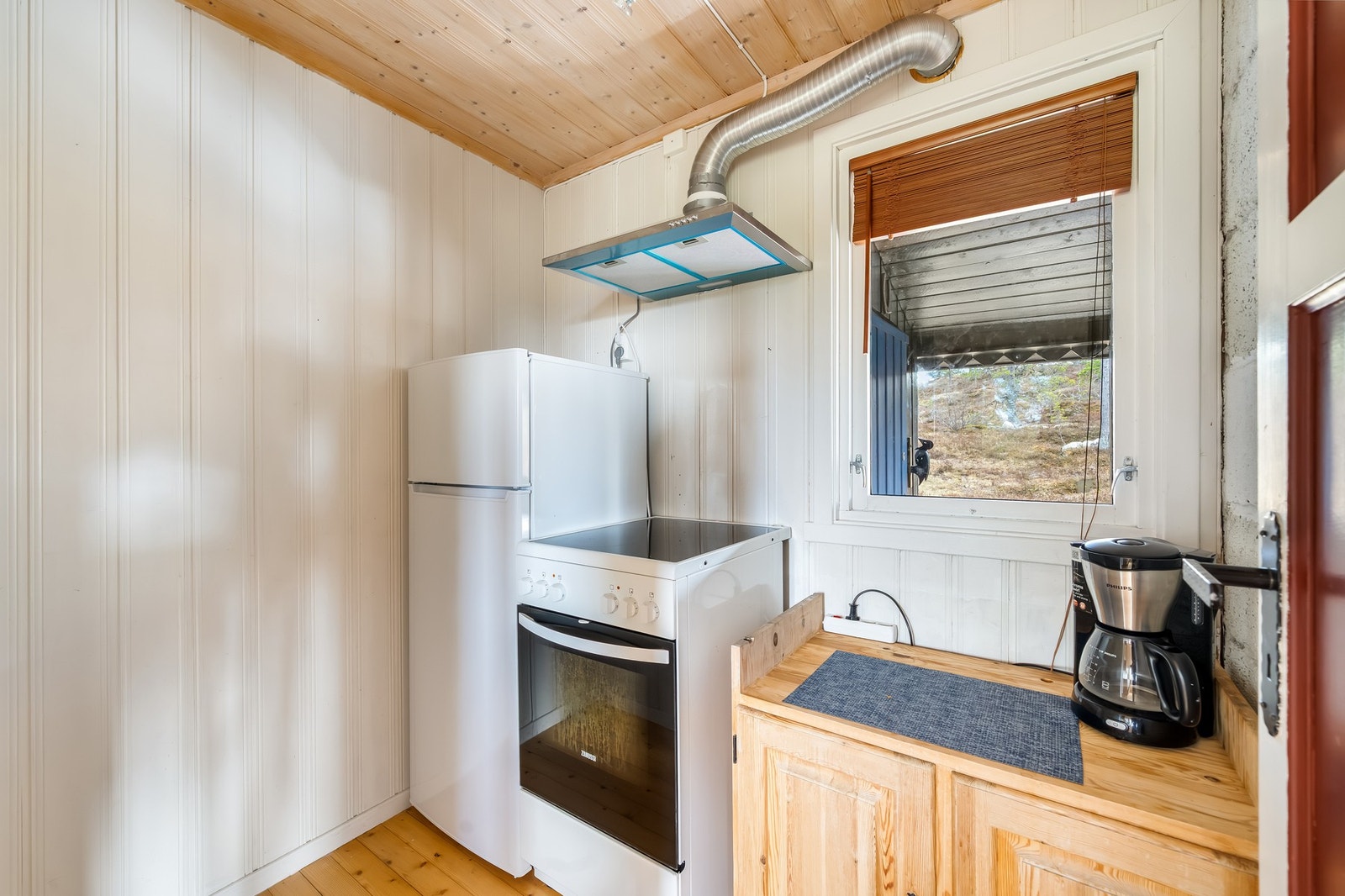 Kjøleskap og steikeovn er plassert i rom ved siden av kjøkken. Galleribilde