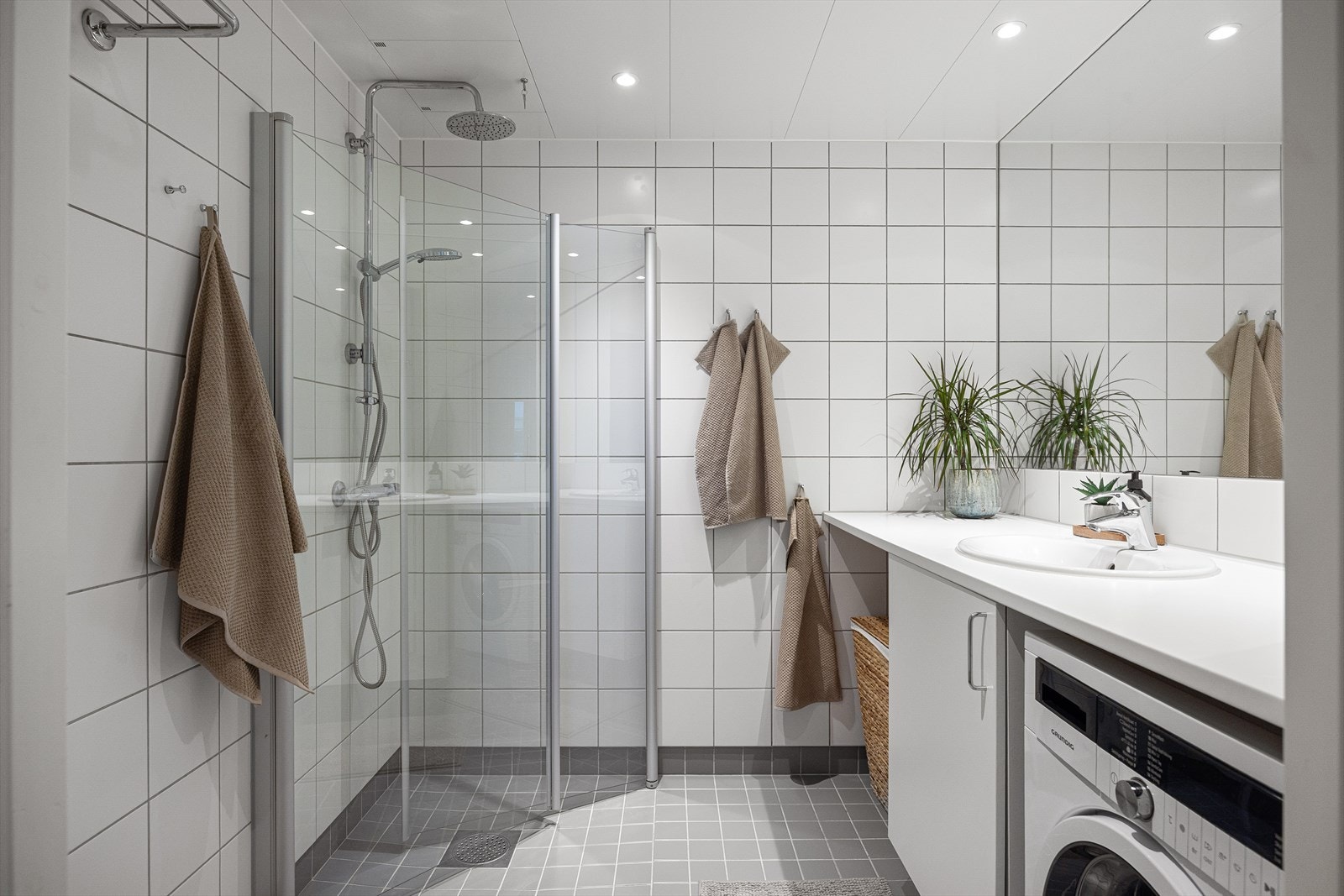 Pent og moderne bad med behagelig gulvvarme som gir en lun og komfortabel følelse. Det er opplegg for vaskemaskin og plass til tørketrommel praktisk plassert under servanten. Galleribilde