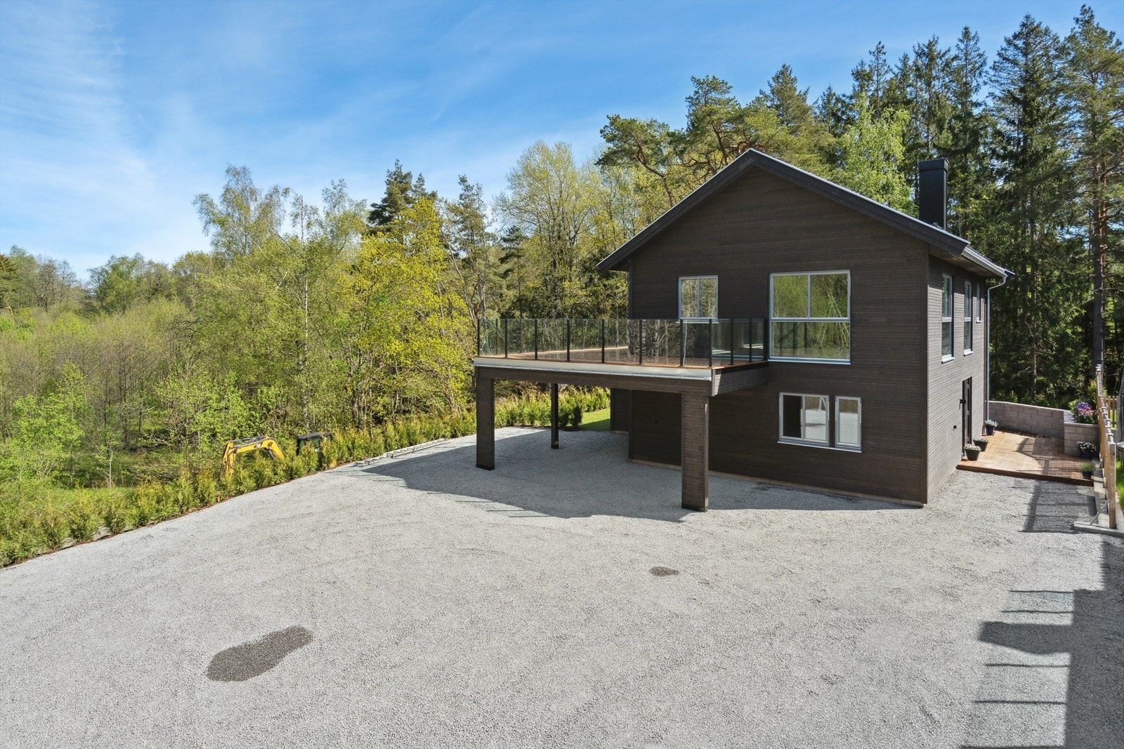 Boligen har gruset innkjørsel og stor carport med stor solrik terrasse på 37 kvm over carporten. Galleribilde