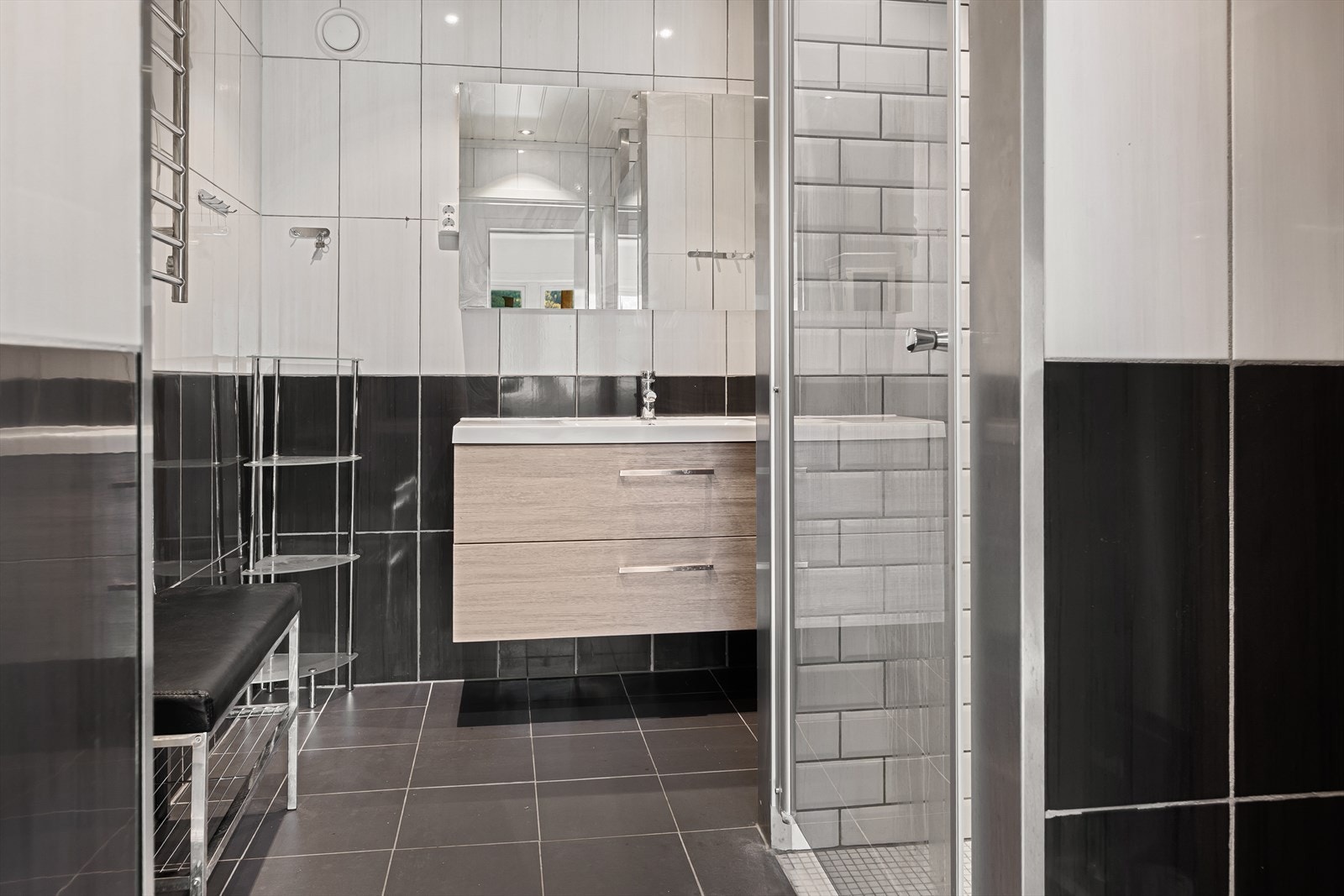 Flislagt bad utstyrt med heldekkende servant med skuffer samt dusjnisje. Galleribilde