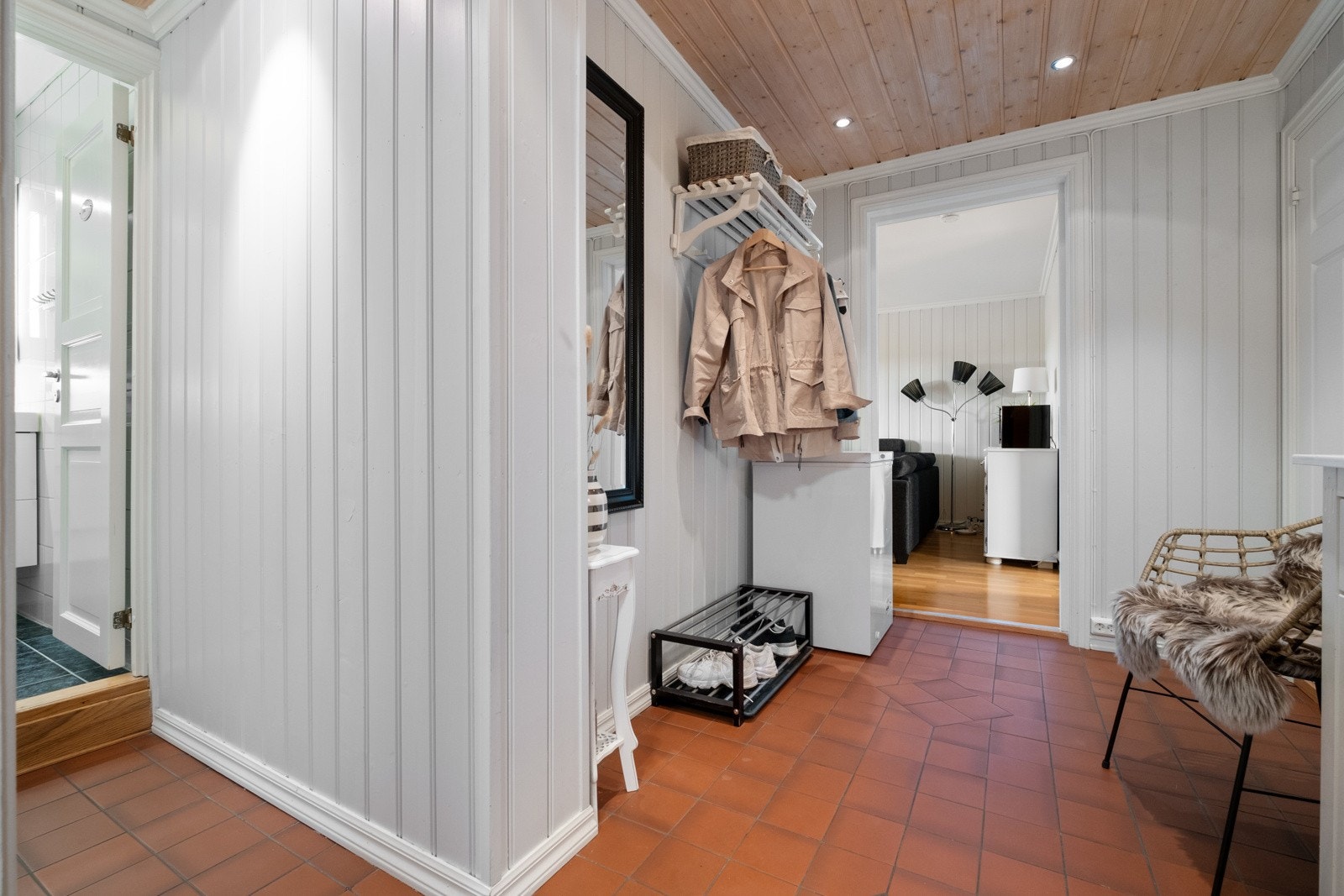 Det er malte panelvegger, trepanel i himling med downlightsbelysning og fliser på gulvet. Galleribilde