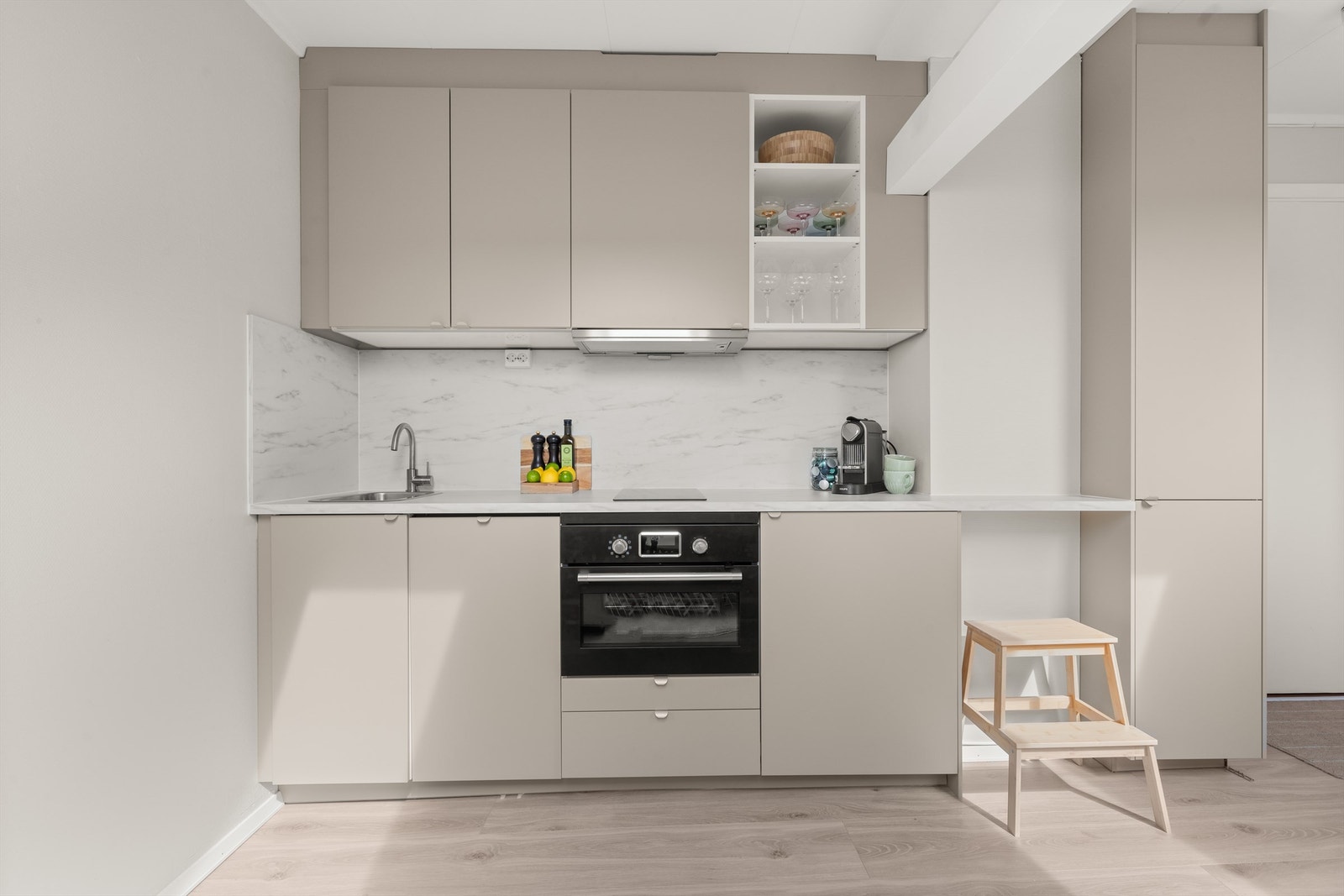 Lekkert og moderne kjøkken som er nytt fra 2023. Innredningen består av slette fronter i en dus og delikat farge og benkeplate av laminat. Det er montert benkeskapsbelysning og stikkontakter under overskap. Galleribilde