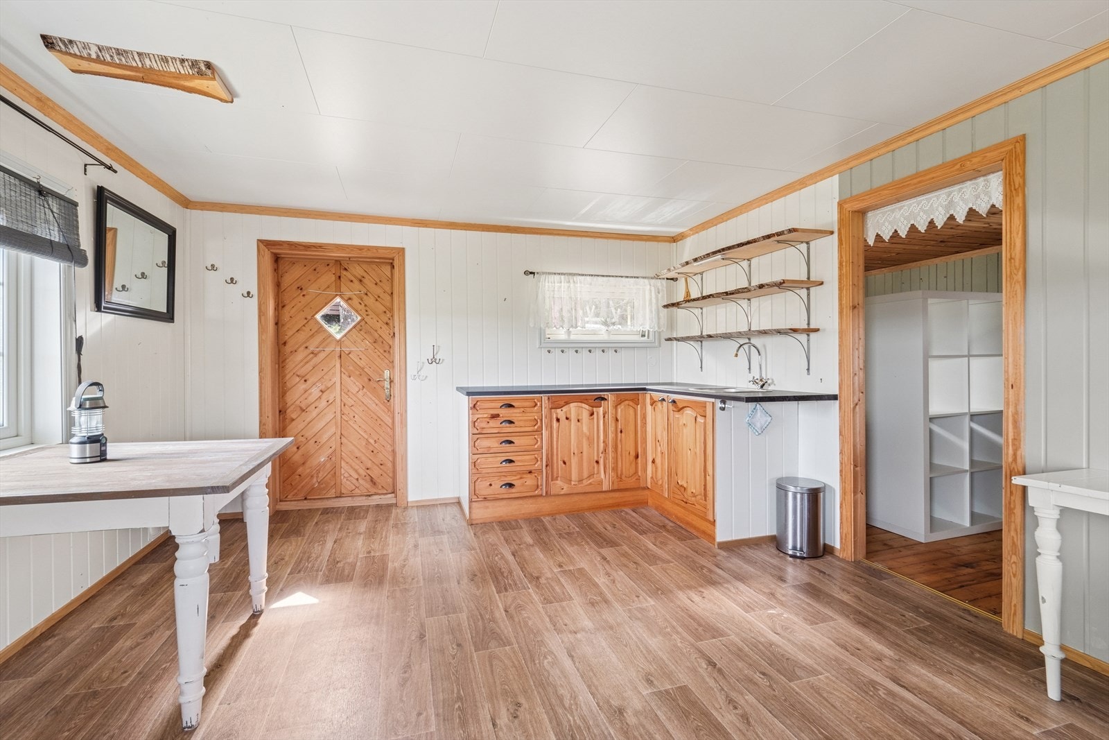 Kjøkkenet er enkelt innredet med profilerte fronter, benkeplate i laminat og utslagsvask med avløp i bøtte. Galleribilde