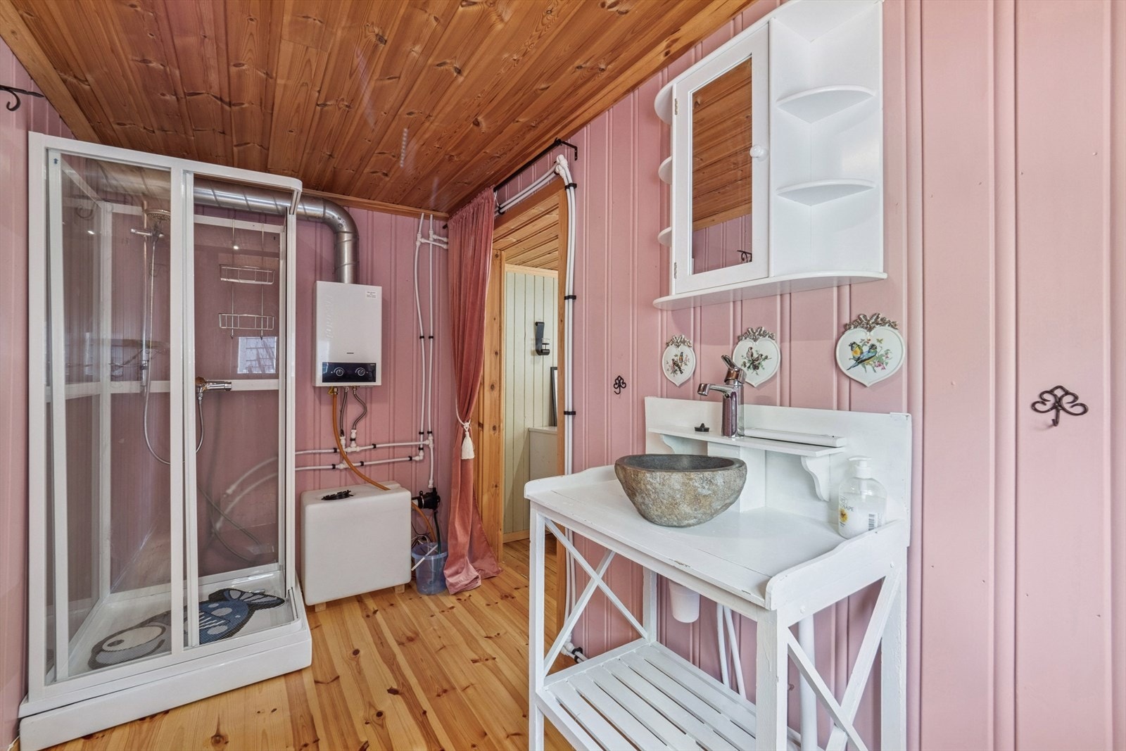 Badet er innredet med dusjkabinett og vask. Vannet kommer fra vanntank med bereder på vegg. Et godt alternativ når man ikke har innlagt vann og avløp. Galleribilde