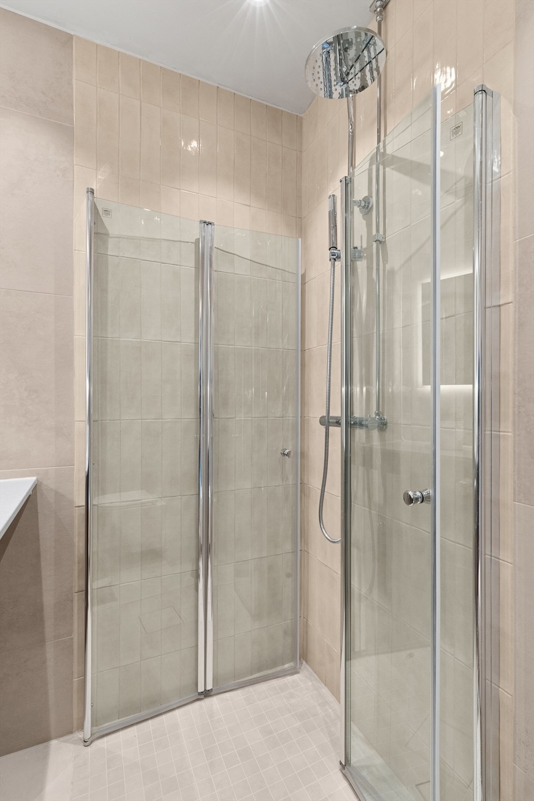 Rommet er praktisk innredet med servant med slette, moderne fronter, veggmontert toalett for et luftig uttrykk, dusjhjørne med glassvegger og opplegg for vaskemaskin. Galleribilde