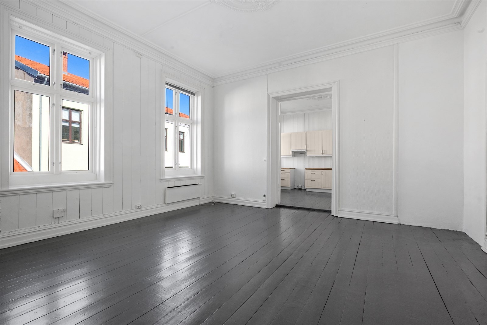 Romslig stue har malt tregulv, malt panel på vegger og malt tak Galleribilde