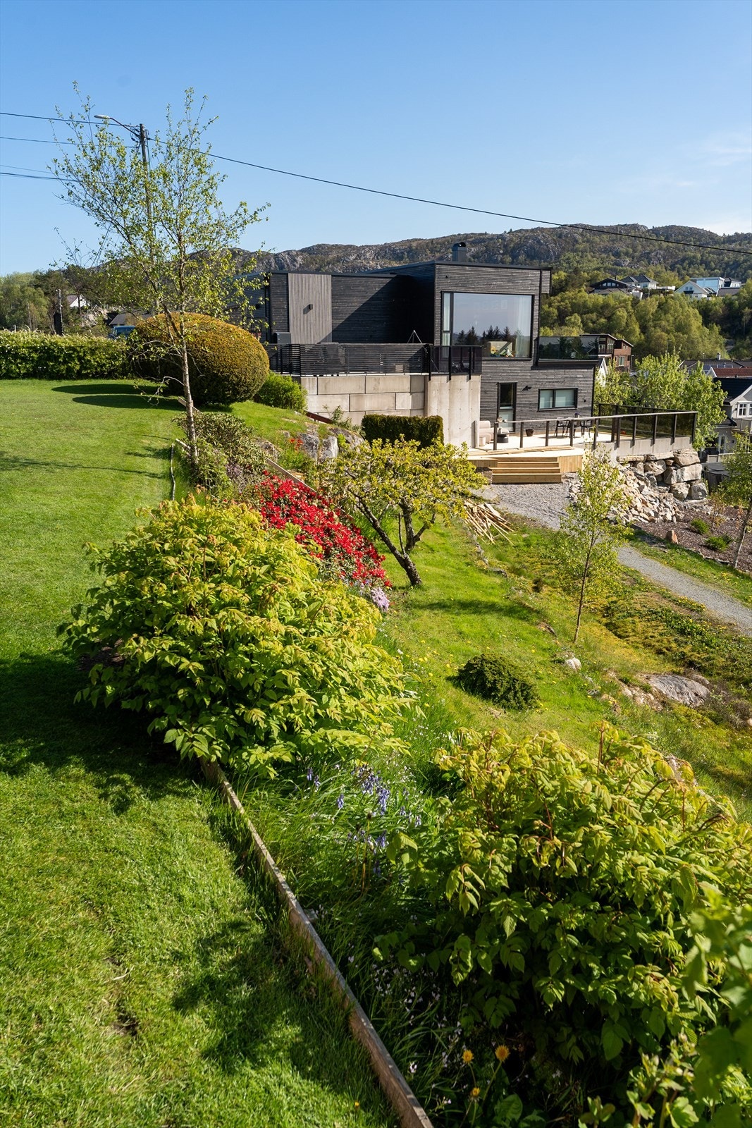 Tomten er flott opparbeidet med velstelt hage med gressplen, blomsterbed og busker. Galleribilde