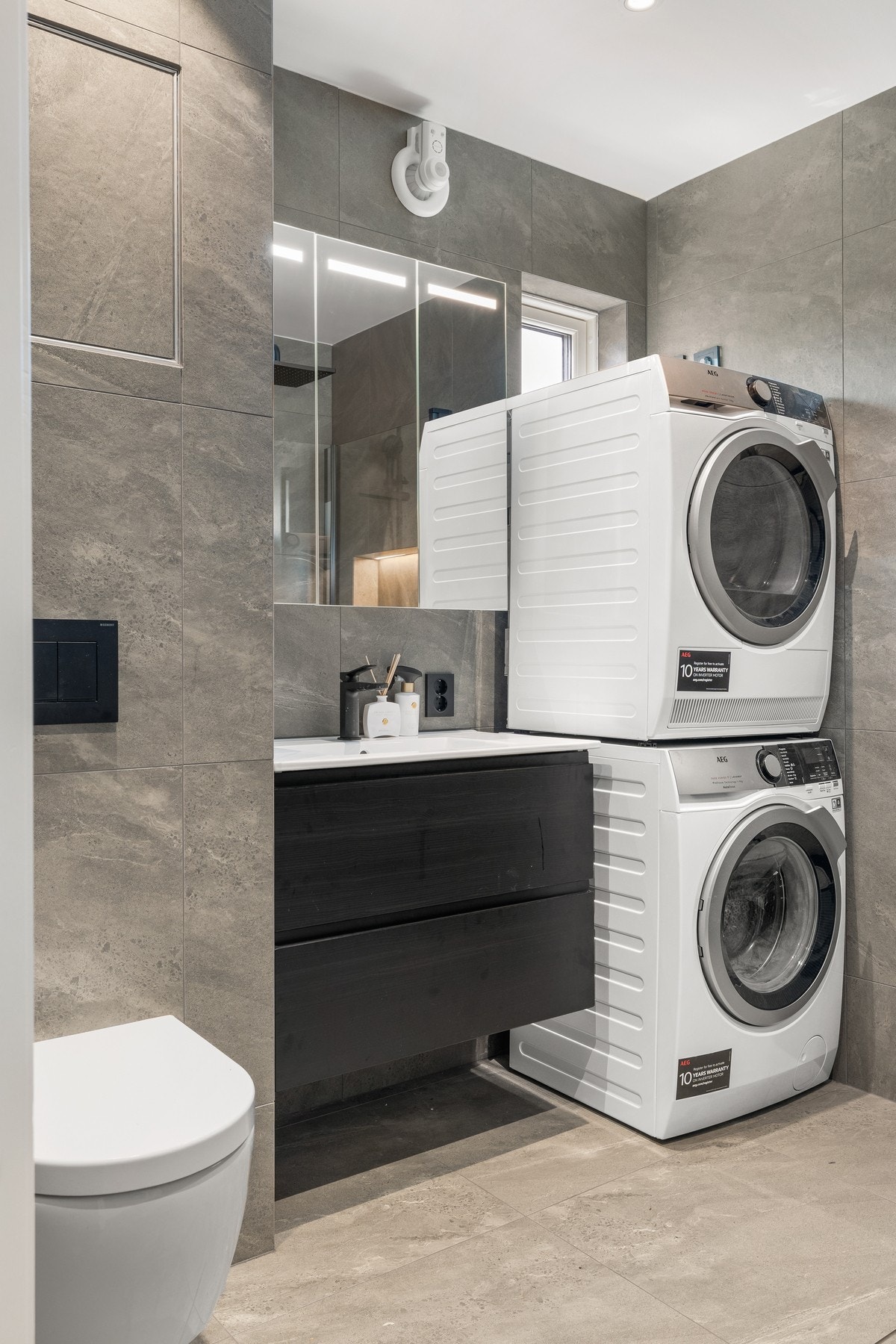 Badet i 1.etg er innredet med vegghengt toalett, servant med skuffeseksjon, dusjhjørnet samt plass og opplegg for vaskemaksin og tørketrommel. Galleribilde