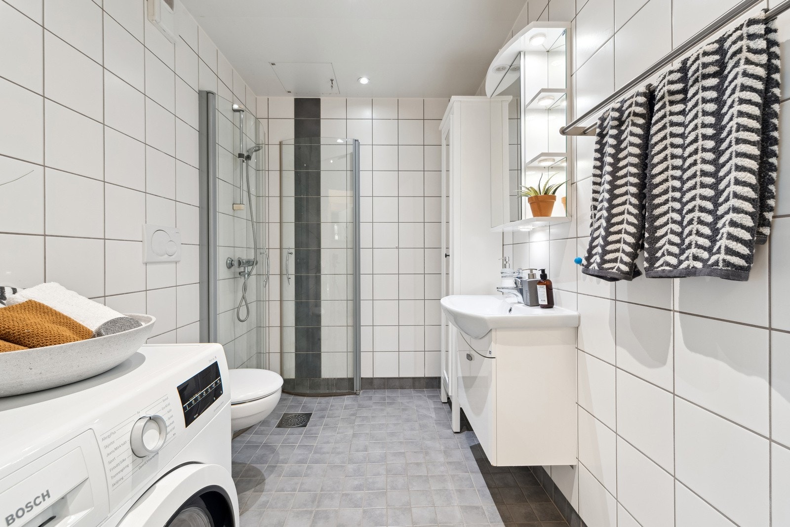 Delikat baderom. Godt valg av fliser. Gulv med varmekabler og tak med downlights. Vaskemaskin vil følge leiligheten. Galleribilde