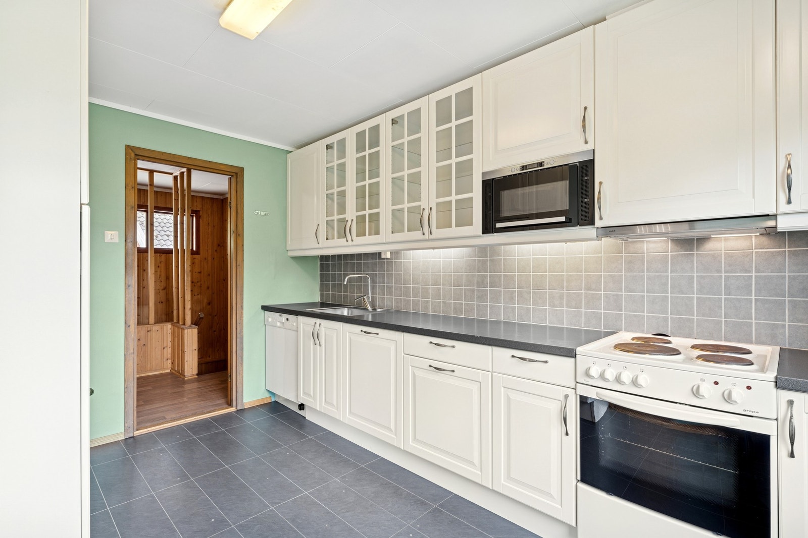 Effektiv kjøkkenløsning med integrerte hvitevarer og plass til frittstående hvitevarer. Galleribilde