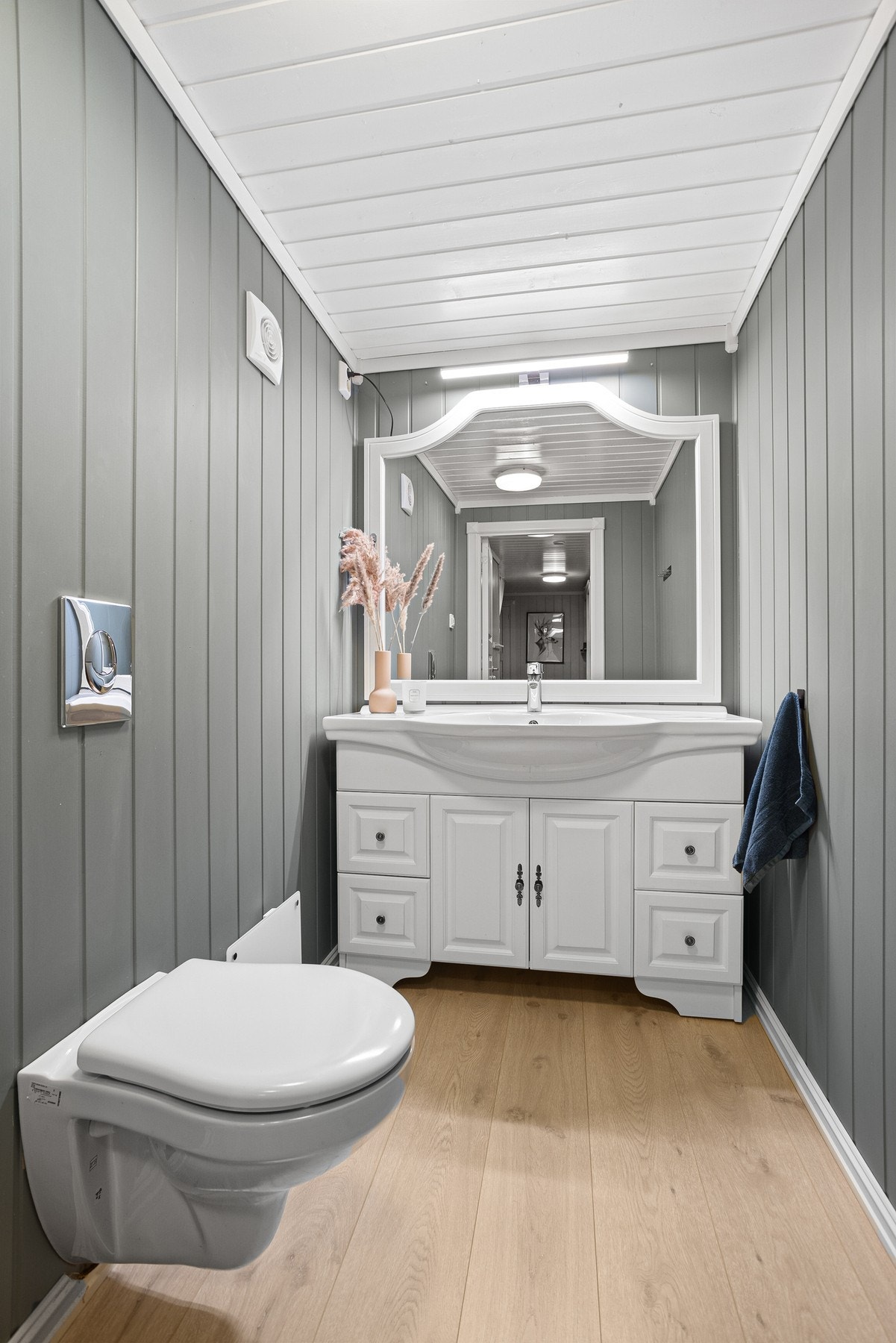 I kjelleren er det et pent, separat wc-rom som ble pusset opp i 2020. Enstavs laminat på gulvet, og i tillegg til et vegghengt toalett har rommet en klassisk, hvit servantinnredning. Galleribilde