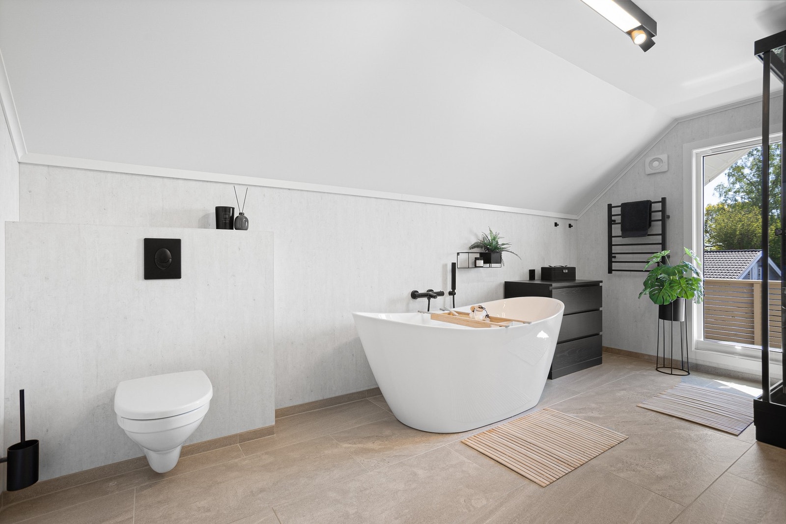 Badet har et moderne badekar og et multifunksjonelt dusjkabinett. Veggene er kledd med lyse våtromsplater, og på gulvet er det store, beige fliser og elektrisk gulvvarme. Galleribilde