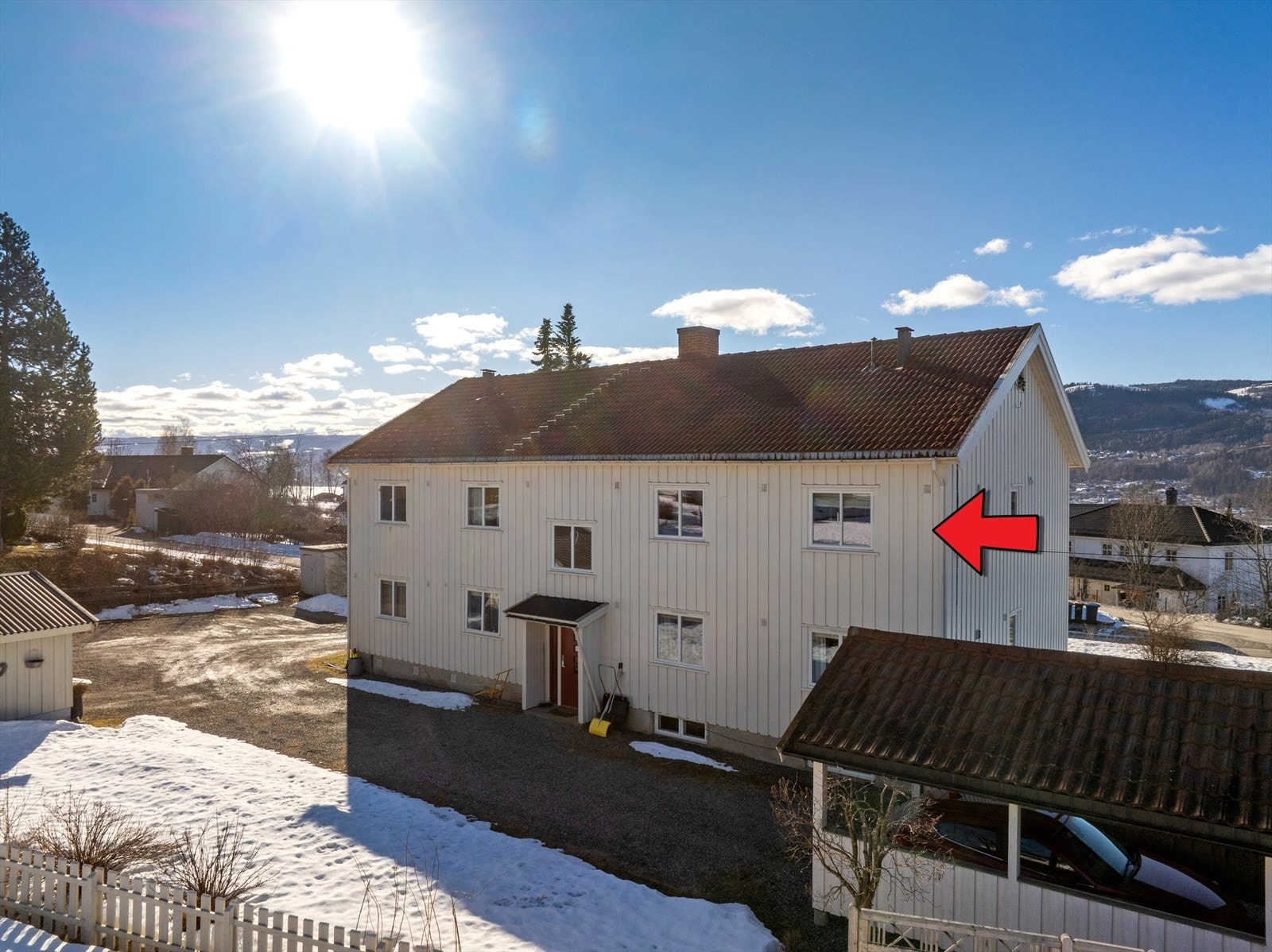 Felles inngang og trappegang med naboer. Gruset gårdsplass utenfor bygget med biloppstillingsplasser og garasjer. Galleribilde