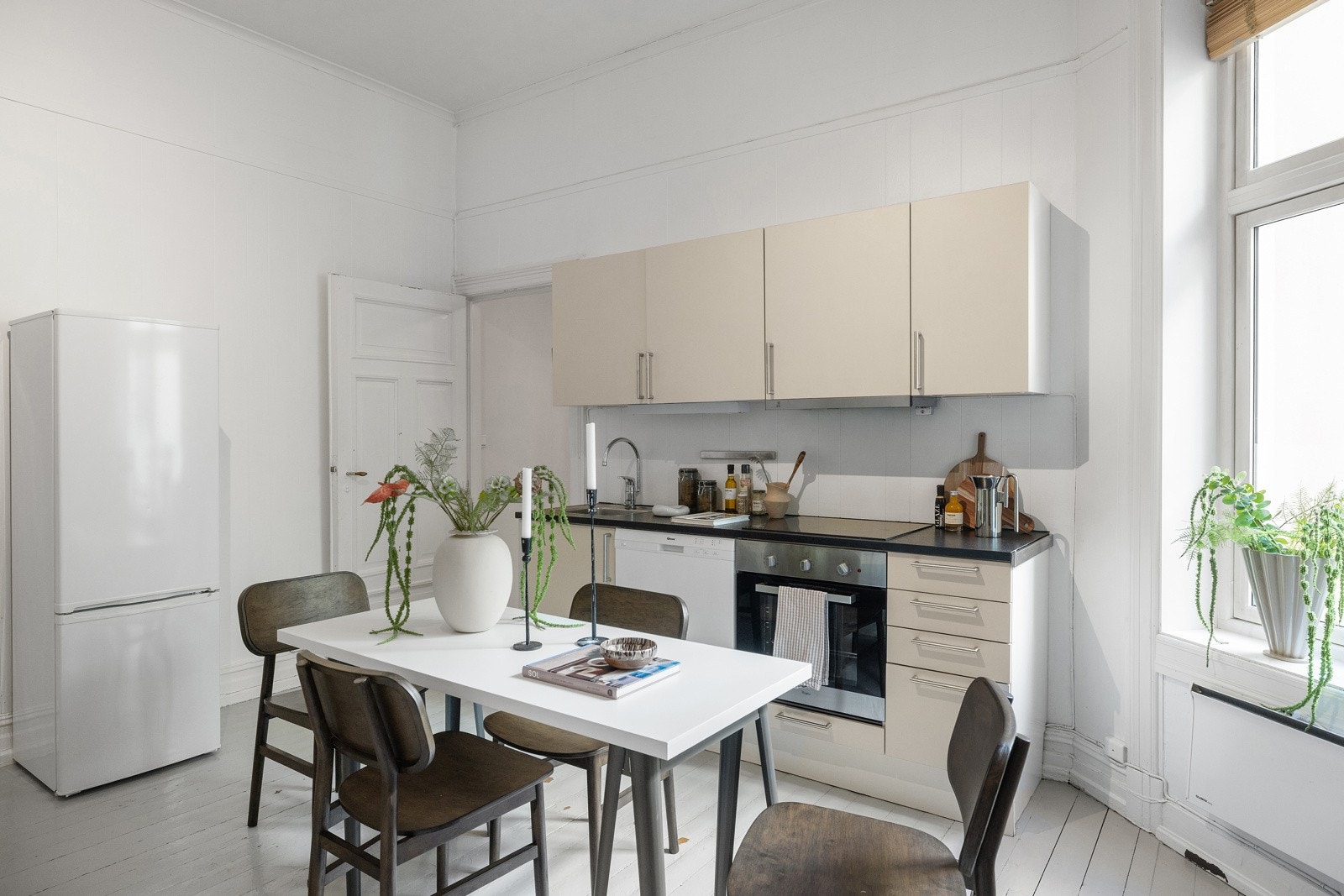 HTH-kjøkkeninnredning med beige glatte fronter og 30mm tykk og mørk laminatbenkeplate med nedfelt vaskekum i børstet stål og ettgreps blandebatteri i rustfritt stål fra Oras. Galleribilde