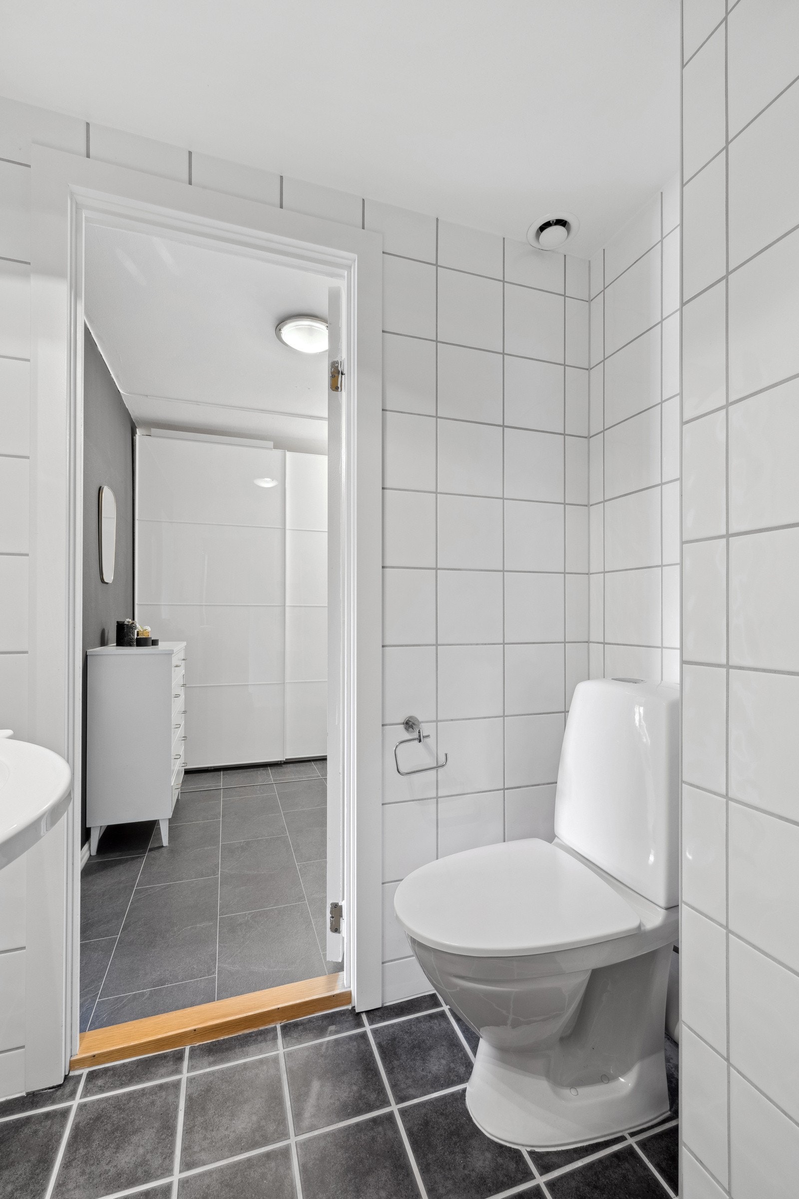 Badet er innredet med vegghengt servantskap med heldekkende servant og ett-greps armatur og et speilskap med overlys over servant. Det er gulvmontert klosett, dusjhjørne med skyvedør av glass og dusjarmatur. Galleribilde