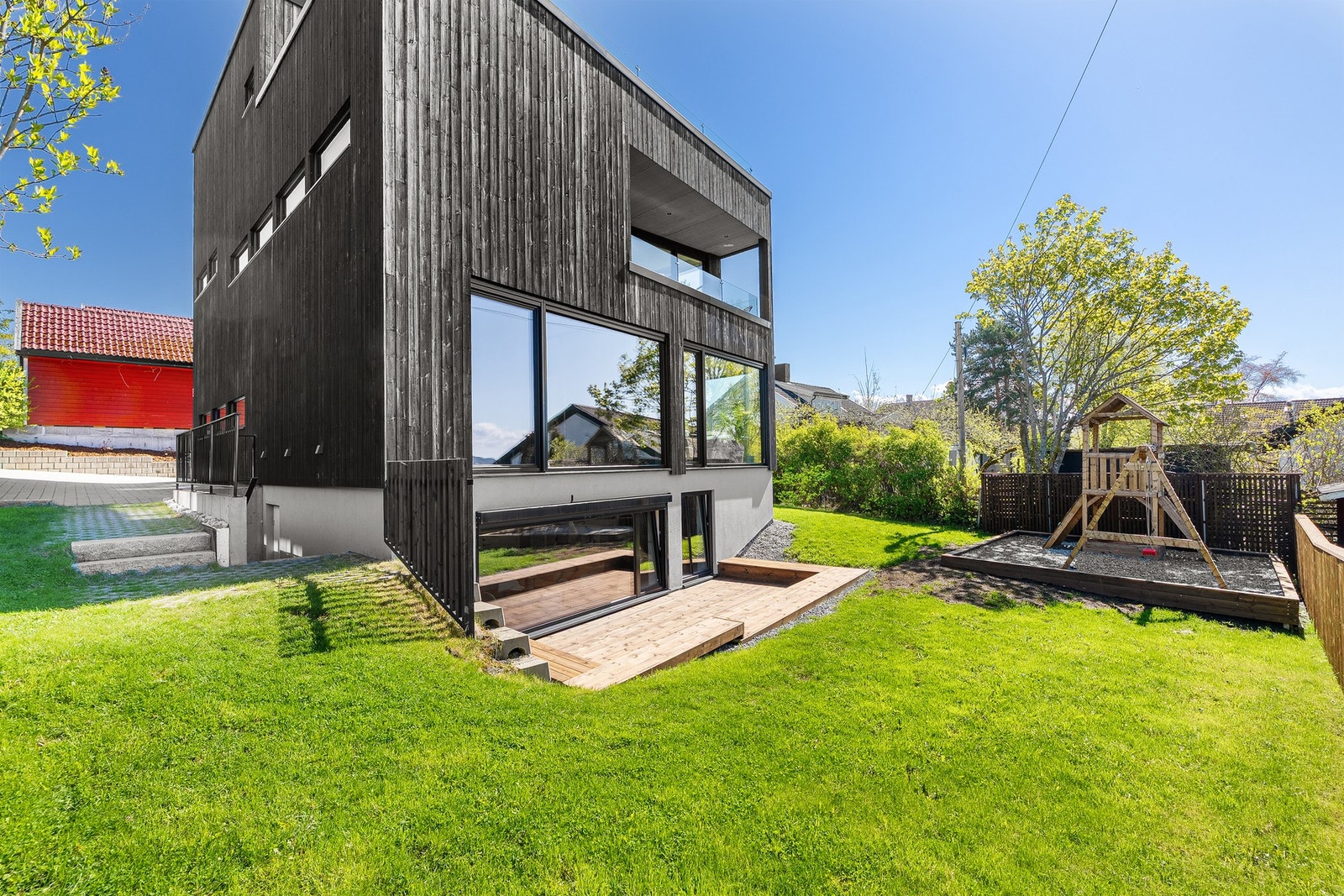 Pent opparbeidet hageområde med lekeplass, plen og terrasse. Galleribilde