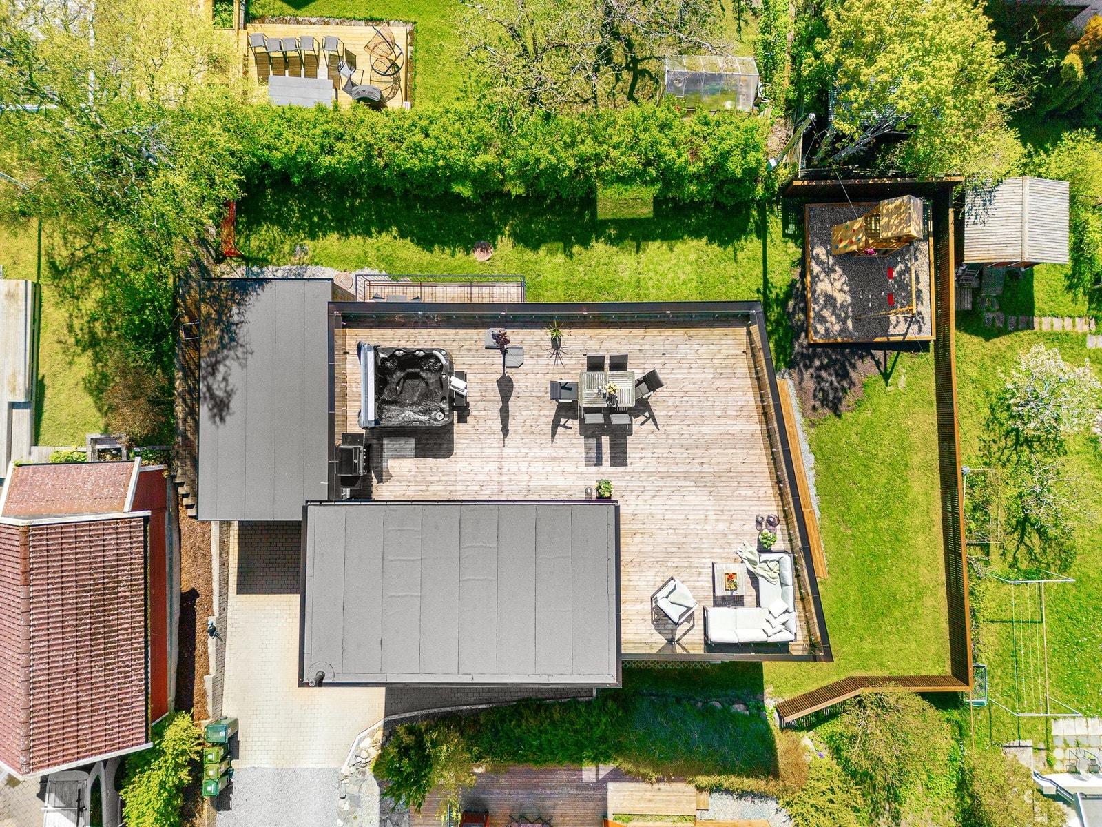 Oversiktsbilde som viser eiendommens imponerende takterrasse, solrike hage og skjermet lekeområde. Galleribilde