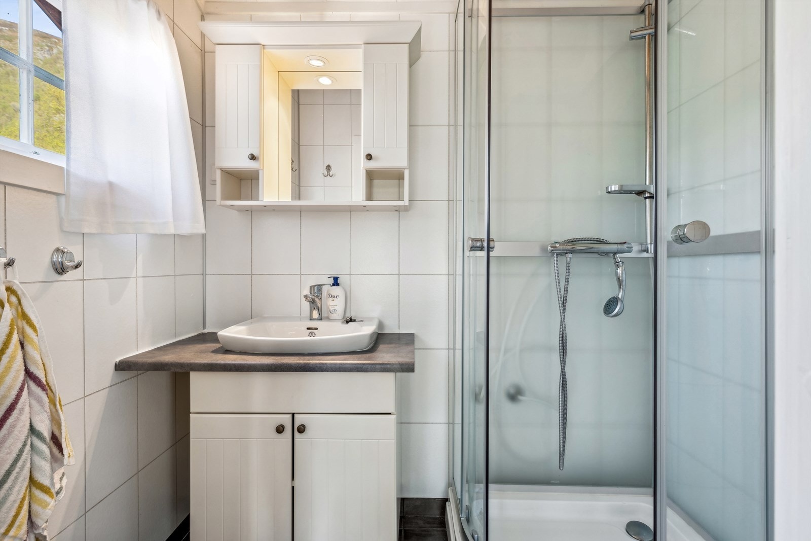 Bad med flis på gulv med behagelig gulvvarme, servant og dusjkabinett Galleribilde