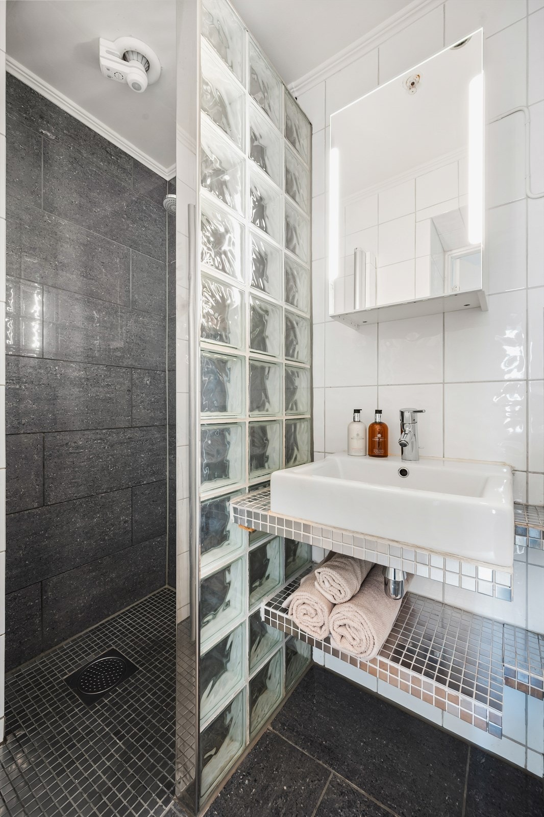 Det er innredet med vegghengt klosett, servant plassert på benkeplate og dusjhjørne med svingbare glassdører. Galleribilde